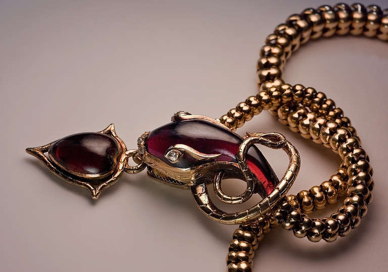 This superb Victorian era gold necklace is designed as a finely carved almandine garnet snake head holding an almandine garnet heart-shaped locket. The snake's eyes and nose are embelished with rose cut diamonds.
The back of the heart-shaped
