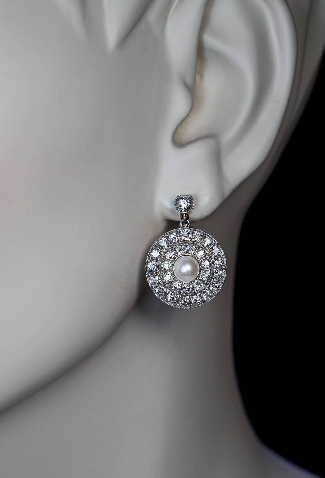 A pair of platinum topped gold earrings, circa 1915, each centered with a 5.6 mm pearl surrounded by two rows of bright white (F-G color) antique round English cut diamonds

Estimated total diamond weight 4 carats

Diameter 18 mm (11/16