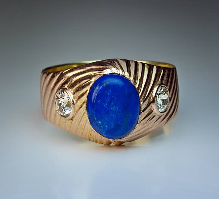 Made in Moscow between 1908 and 1917

The 14K gold ribbed ring is centered with an oval cabochon cut medium blue lapis lazuli flanked by two bezel-set old European cut diamonds (approximately 0.54 ct total weight). 

Marked with 56 zolotnik gold