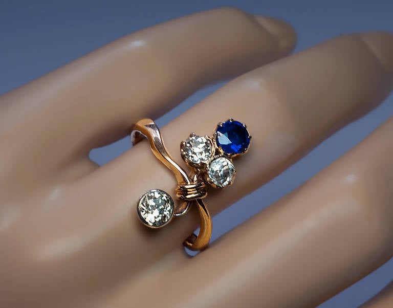 Russian, circa 1900

The 14K rose gold ring is designed as a stylized ribbon-tied flower spay, prong-set with a very fine blue sapphire (5-5 x 3.6 mm, approximately 0.65 ct) and three old European cut diamonds: two prong-set and one in a silver