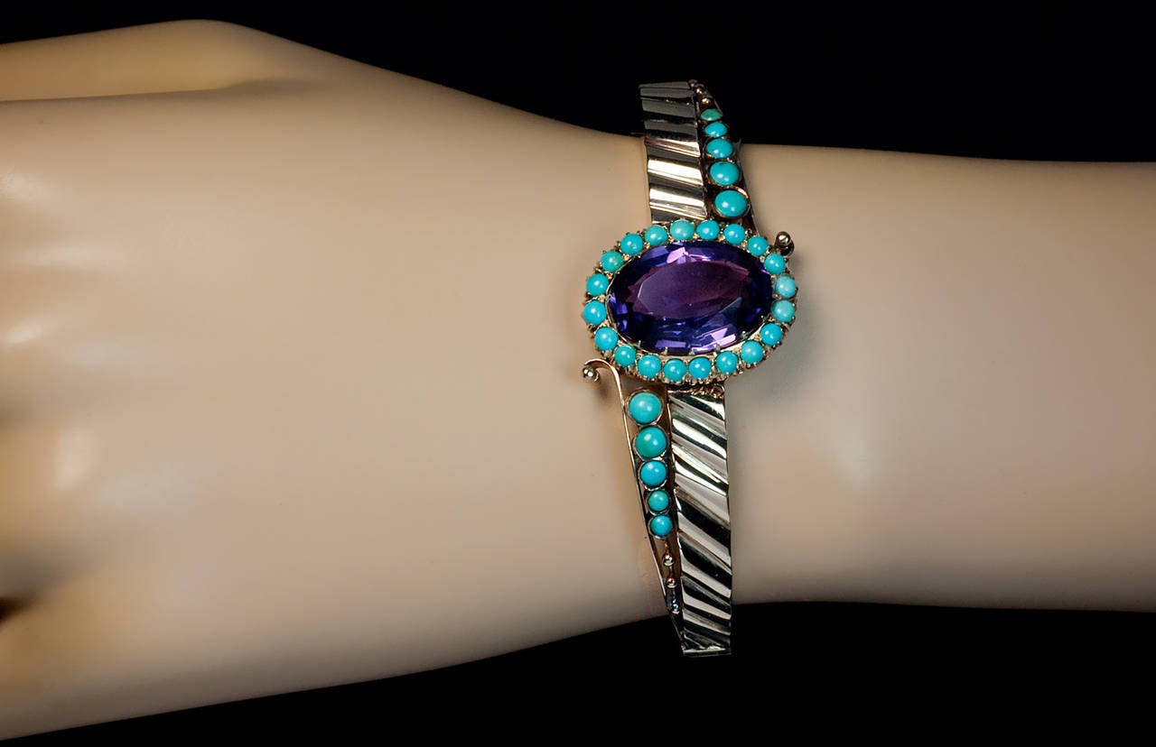 Made in Moscow in the 1880s - early 1890s

The 14K gold ribbed bracelet is centered with an oval faceted amethyst (17.5 x 12.2 x 7.7 mm, approximately 8.71 ct) surrounded by prong-set turquoise, and further flanked by two turquoise-set