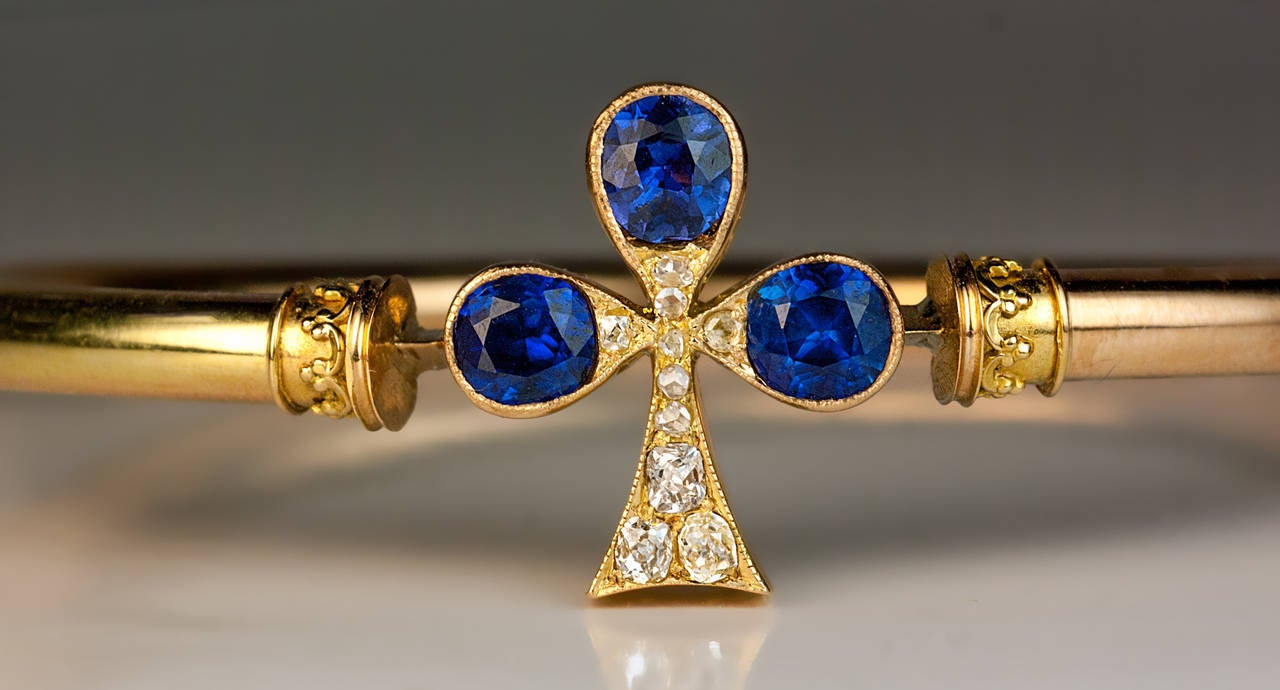 made in St. Petersburg between 1882 and 1898

 The 14K gold Victorian era bracelet is centered with what can be interpreted as a clover or the playing cards symbol for clubs set with three faceted sapphires of an excellent royal blue color