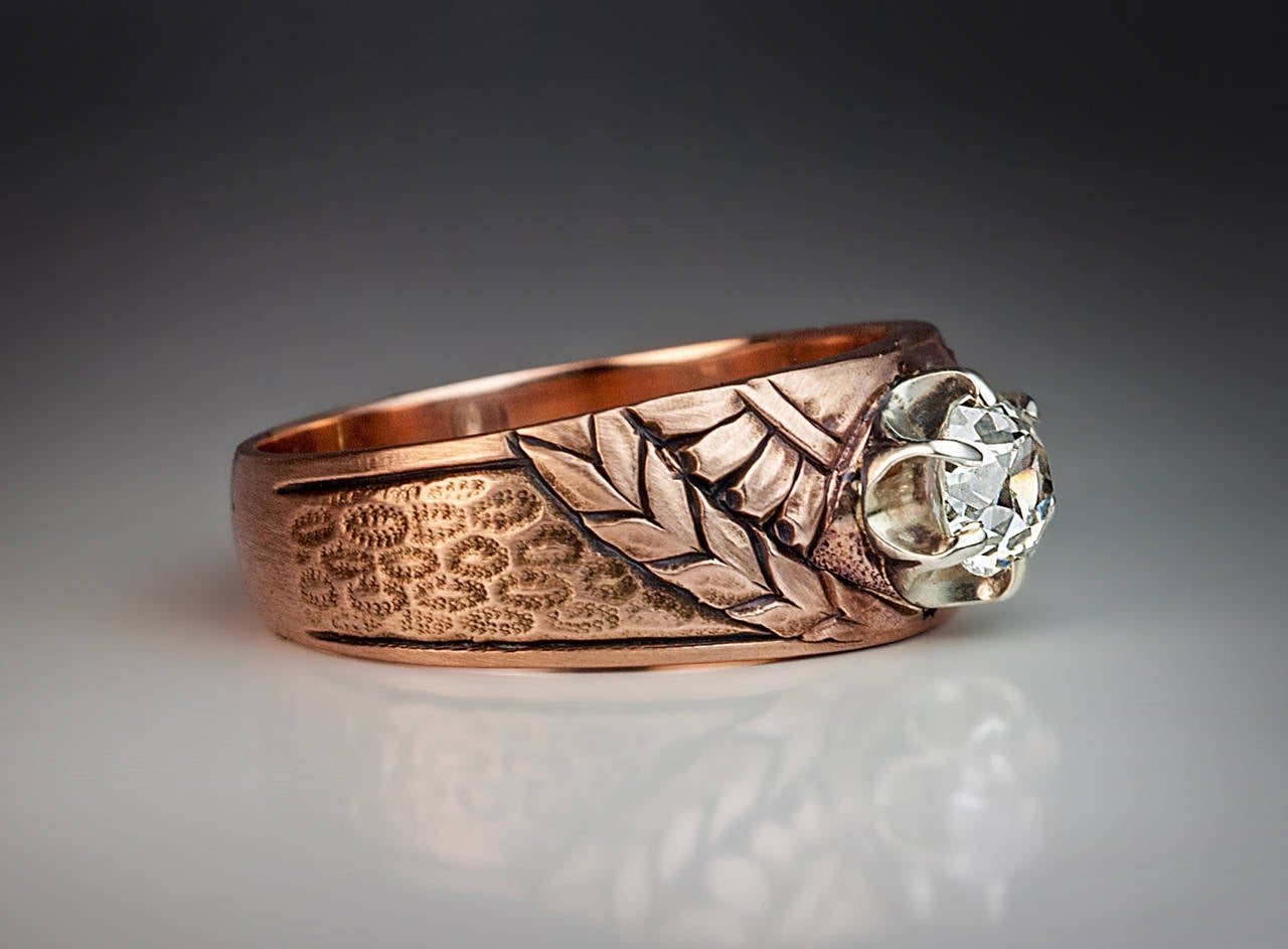 The 14K rose gold ring with chased and engraved decoration in the Russian Modern style of the 1910s features a sparkling old cushion cut diamond (5.5 x 5.45 x 3.3 mm, approximately 0.76 ct, H color, VS1 clarity) prong-set in a silver setting.

