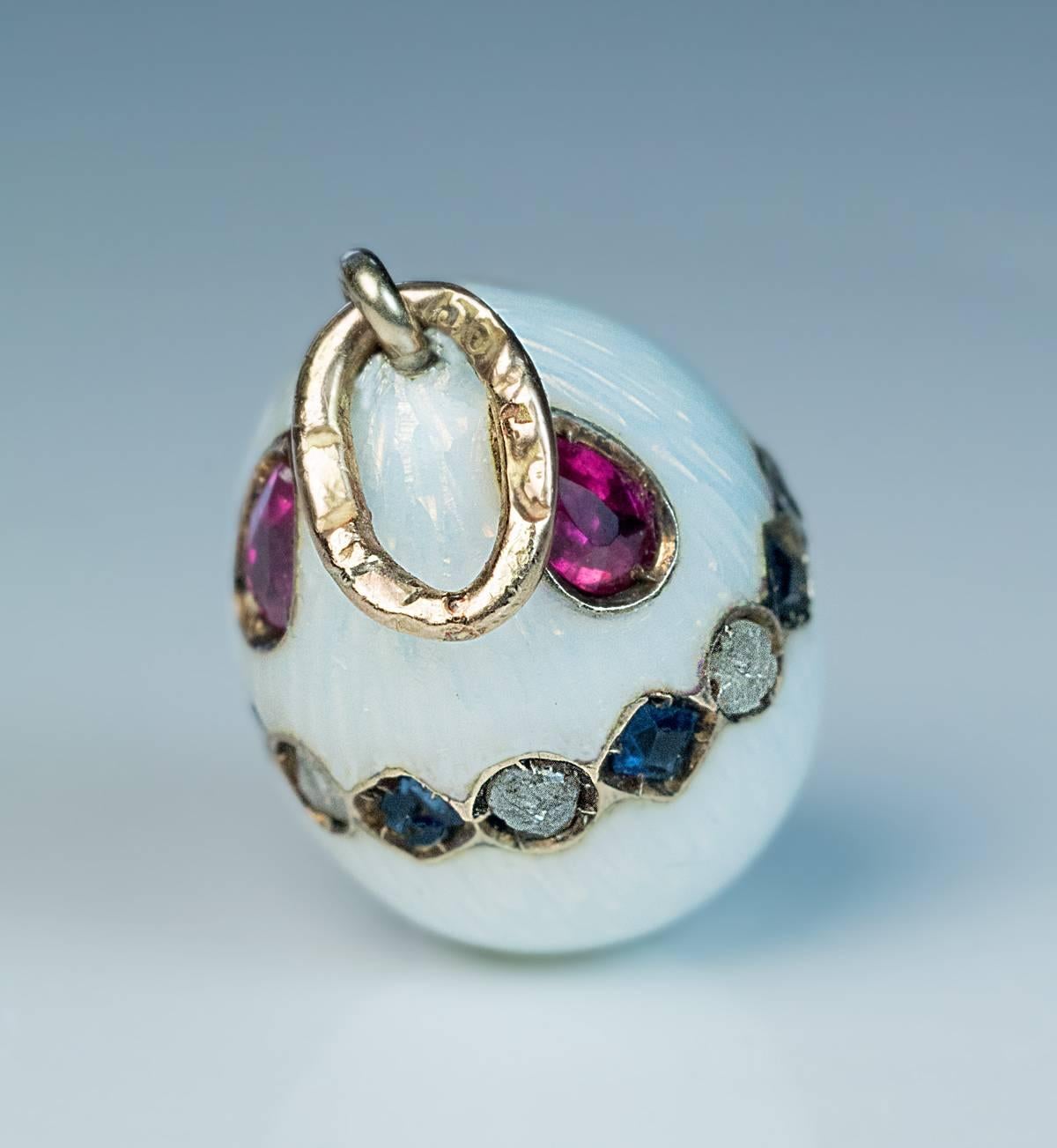made between 1908 and 1917

The egg is covered with a white guilloche enamel and embellished with a band of step cut sapphires & rose cut diamonds, and three drop shaped rubies.
Marked on the gold suspension ring with 56 zolotnik (14K) old