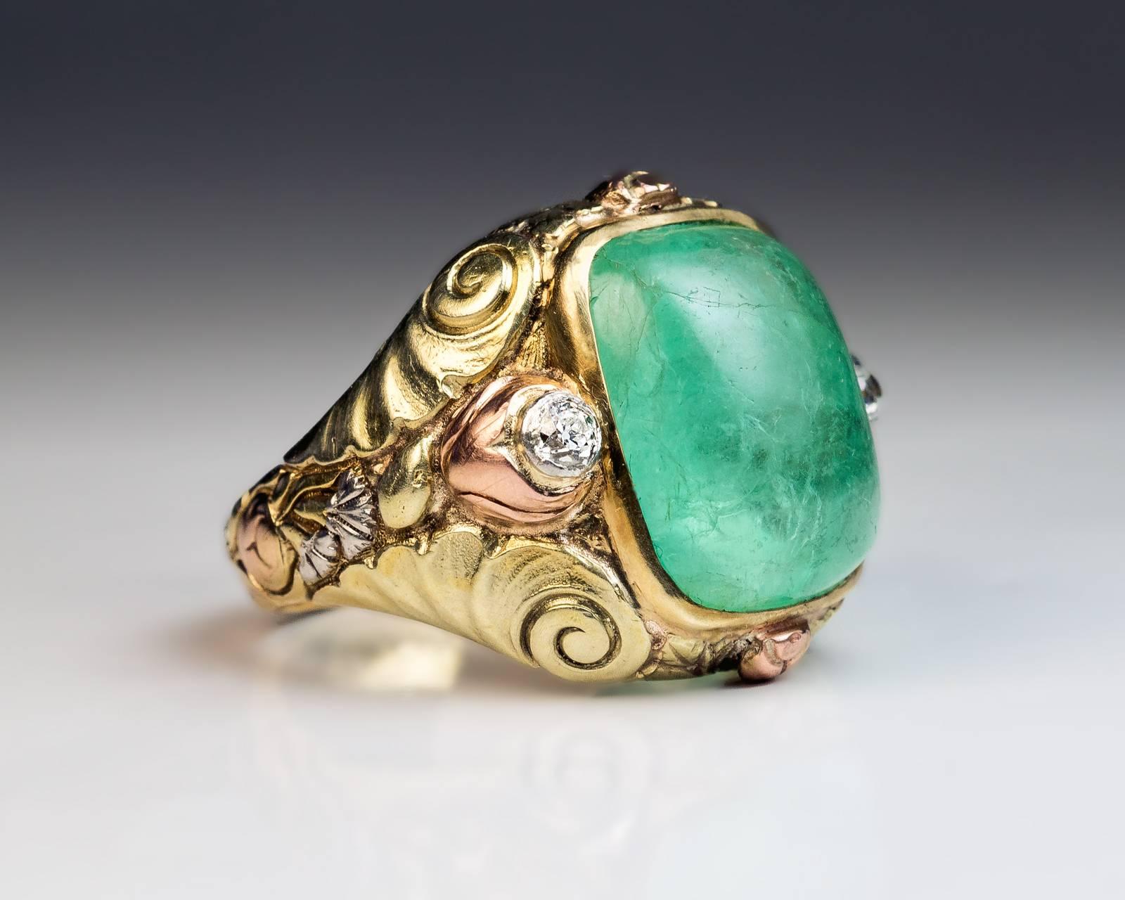 A vari-color gold ring with superbly carved stylized floral designs in Art Nouveau taste bezel-set with a sugar loaf emerald (16 x 13.5 x 8.85 mm, approximately 14.30 ct) flanked by two old European cut diamonds.

The engraved inscription inside