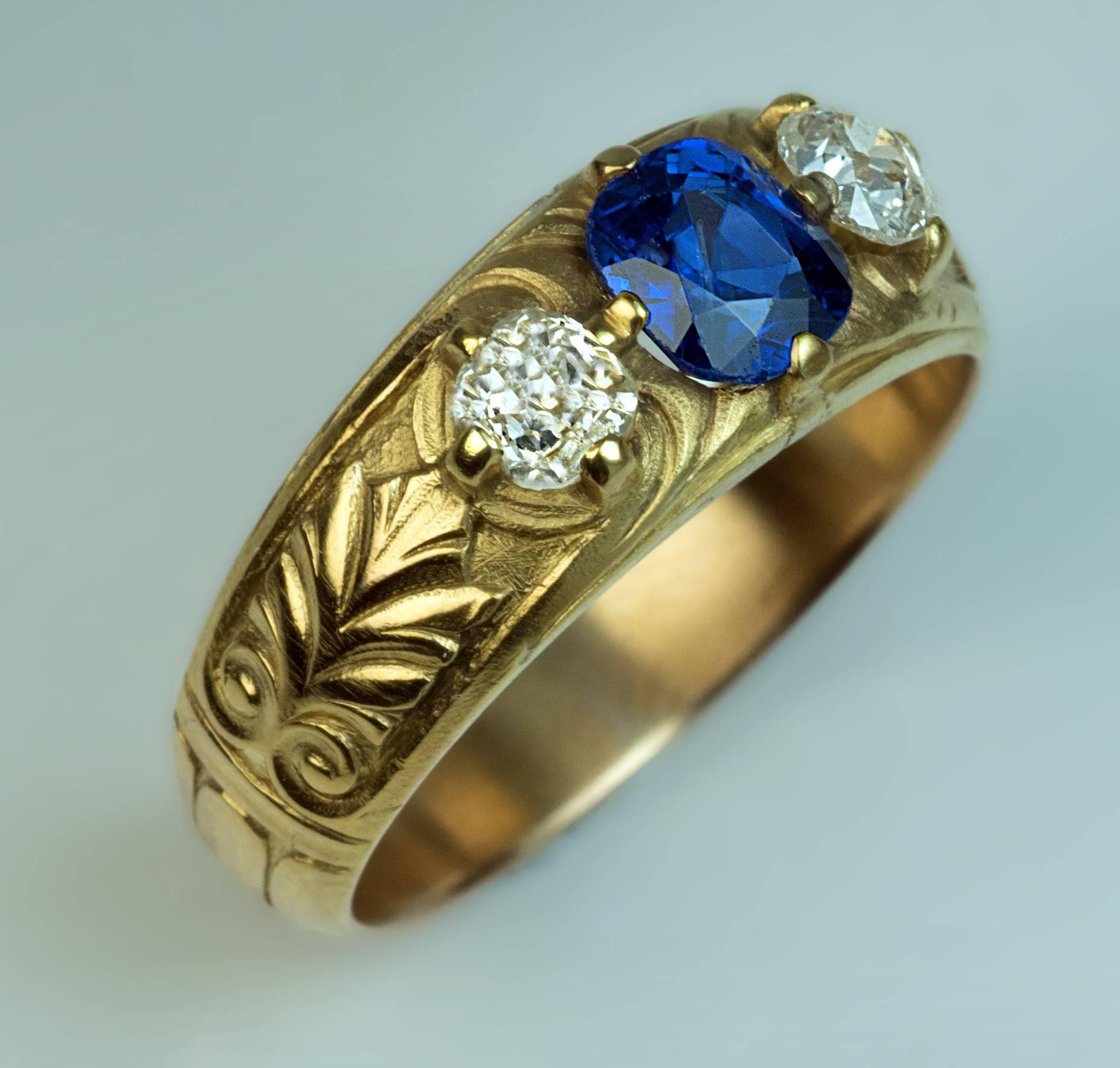 made in Moscow between 1908 and 1917

14K gold ring centered with a natural unheated sapphire of a superb royal blue color (approximately 1 carat) between two old cushion cut diamonds (estimated total weight 0.50 ct), flanked by a pair of carved