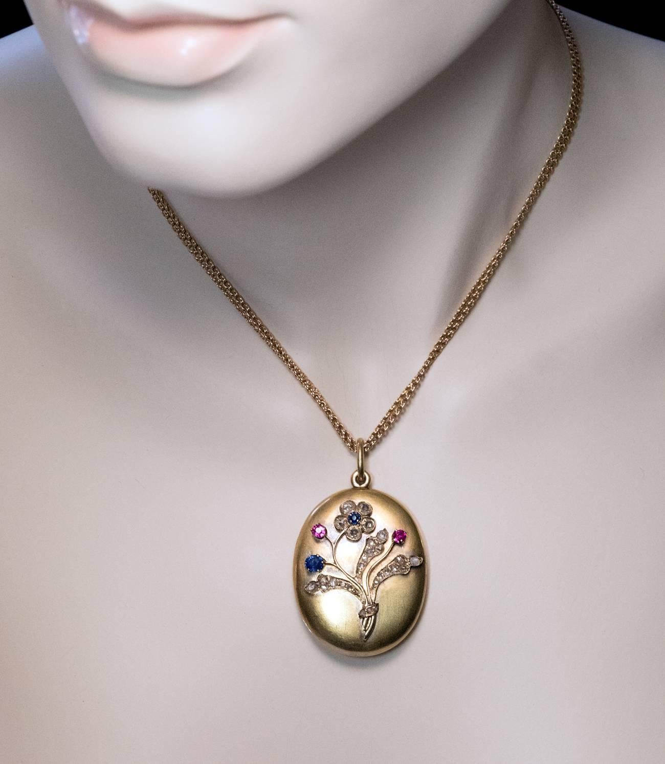 Made in St. Petersburg between 1904 and 1908

A 14K matte green gold locket is decorated with a stylized flower in Art Nouveau taste embellished with old rose-cut diamonds, two rubies and two blue sapphires.

The interior is set with a pair of