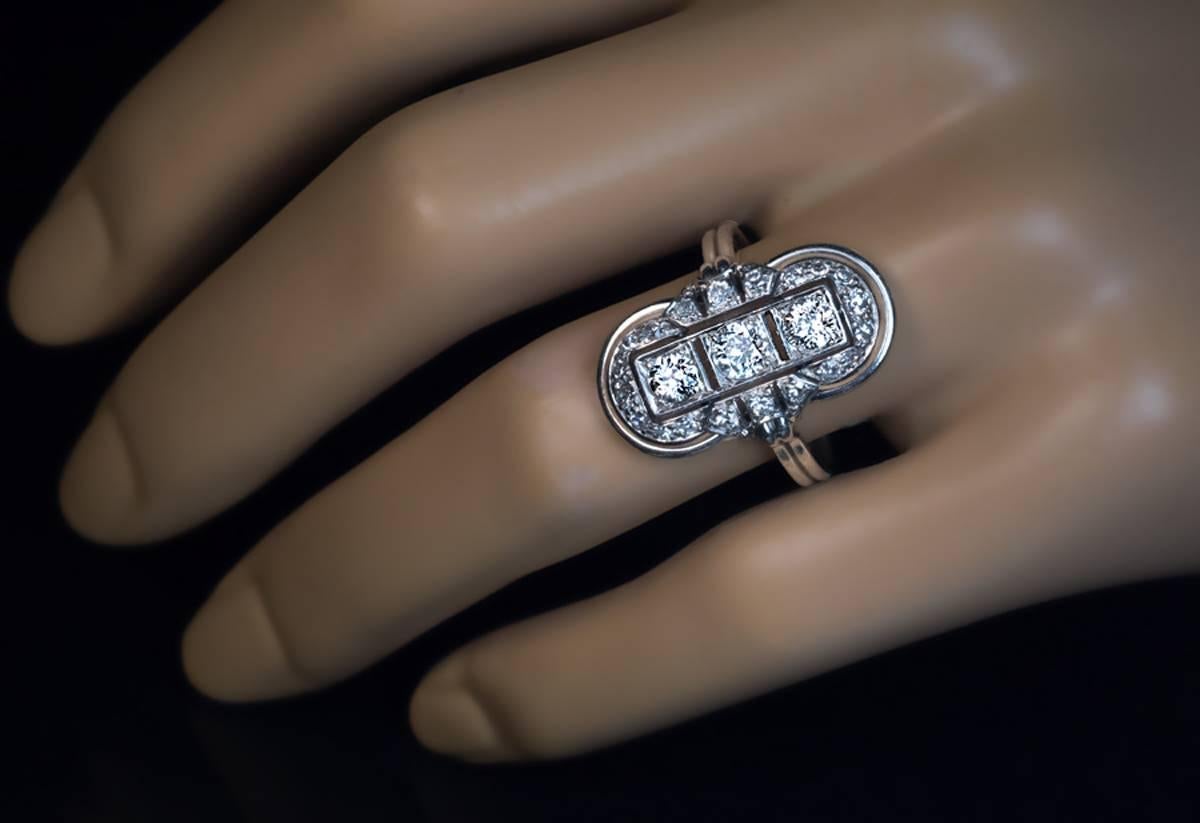 Russian, made in St. Petersburg in the 1930s

A platinum ring is vertically set with three bright white old European cut diamonds (G-H color, VS2-SI1 clarity, approximately 0.21 ct, 0.22 ct and 0.22 ct), surrounded by an ornate frame embellished