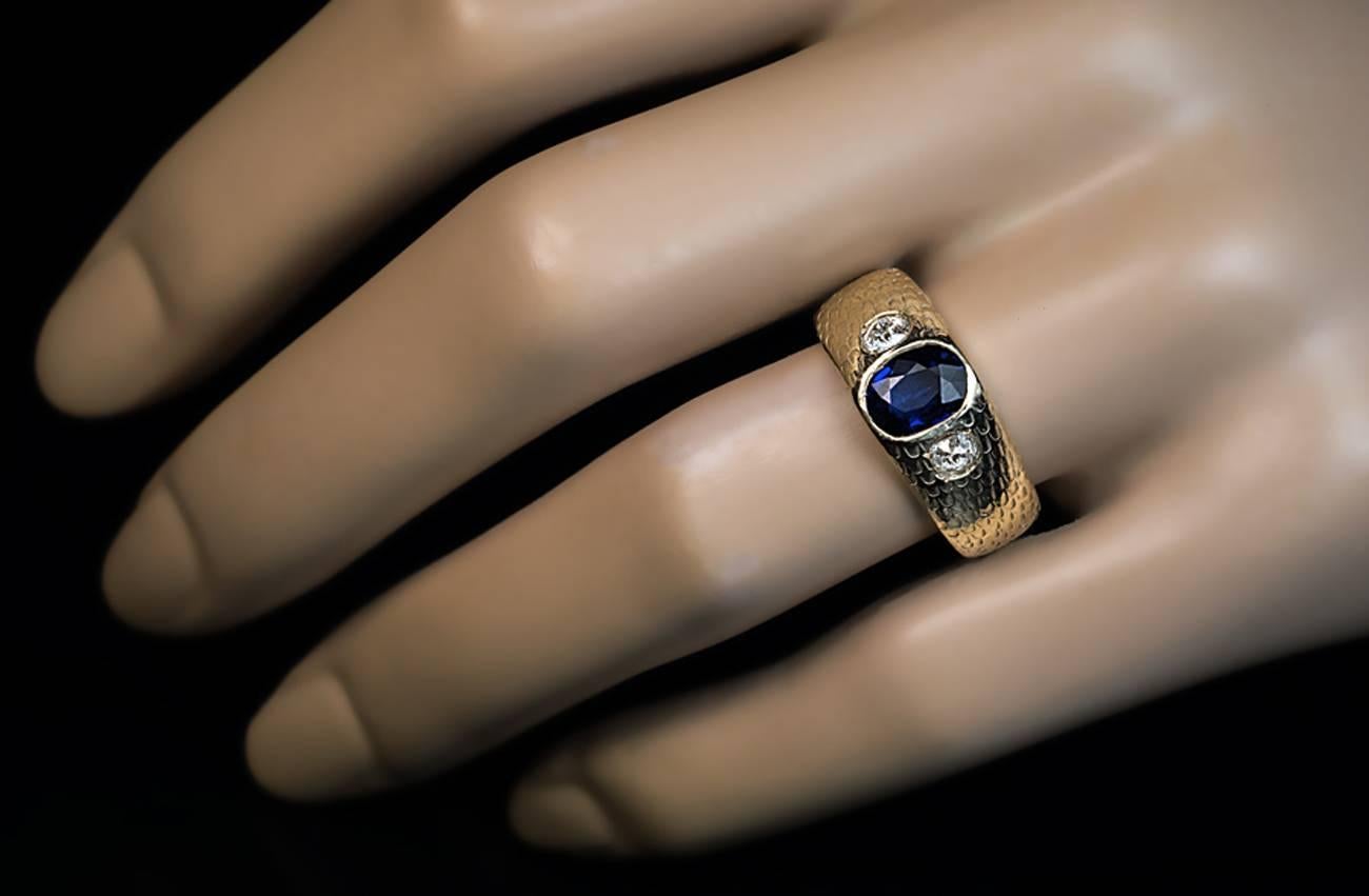 Made in St. Petersburg between 1908 and 1917

A 14K greenish-yellow gold ring is engraved to imitate fish or snake scale. The ring is centered with a bezel-set antique cushion cut natural blue sapphire (7.2 x 5.8 x 2.7 mm, approximately 1 carat),