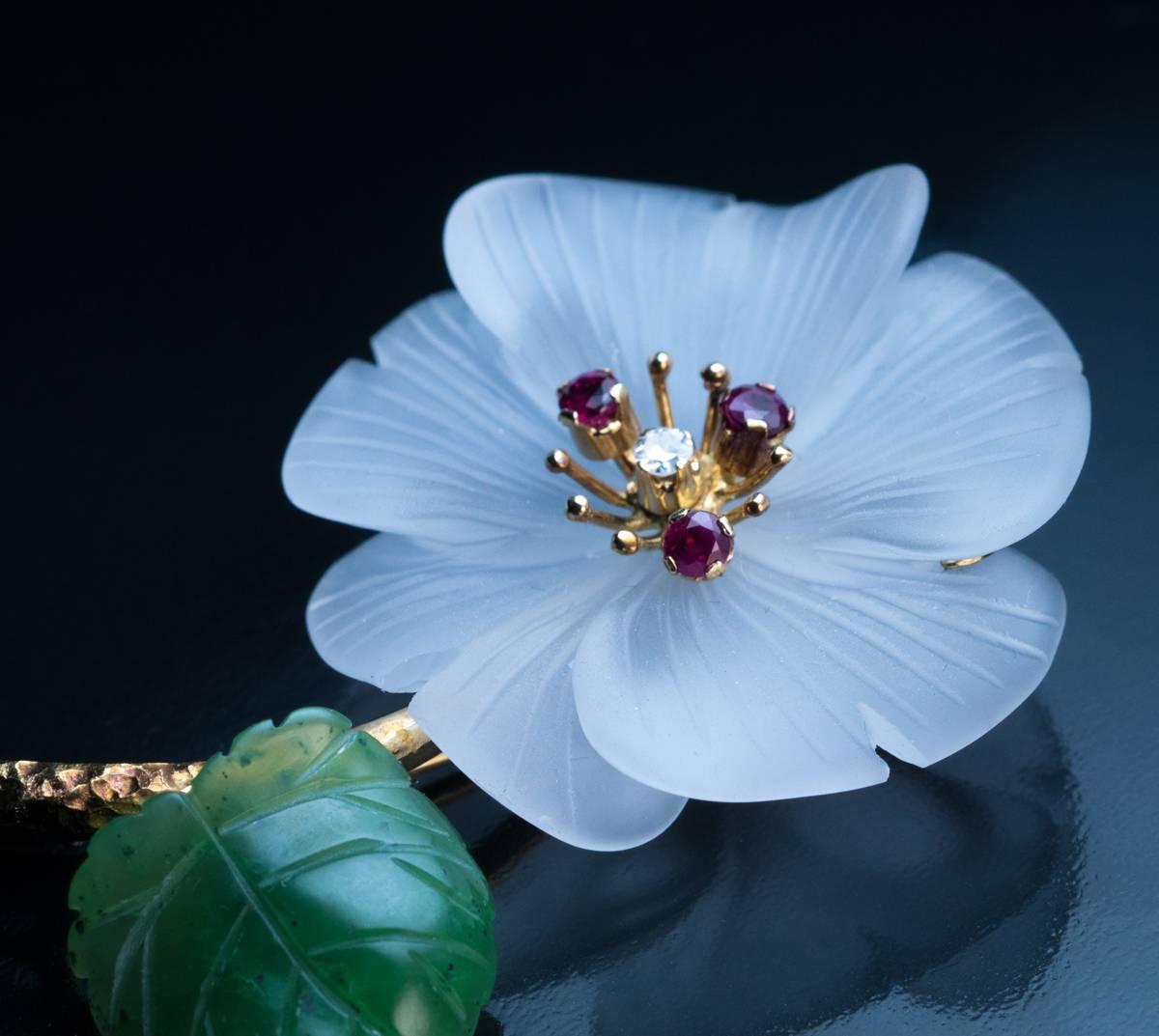 Made in Vienna, Austria in the 1950s

A superbly carved frosted rock crystal flower with a carved nephrite jade leaf is mounted on a textured 14K gold stem.  The flowerhead is embellished with three rubies and a diamond.

Marked with 585 gold