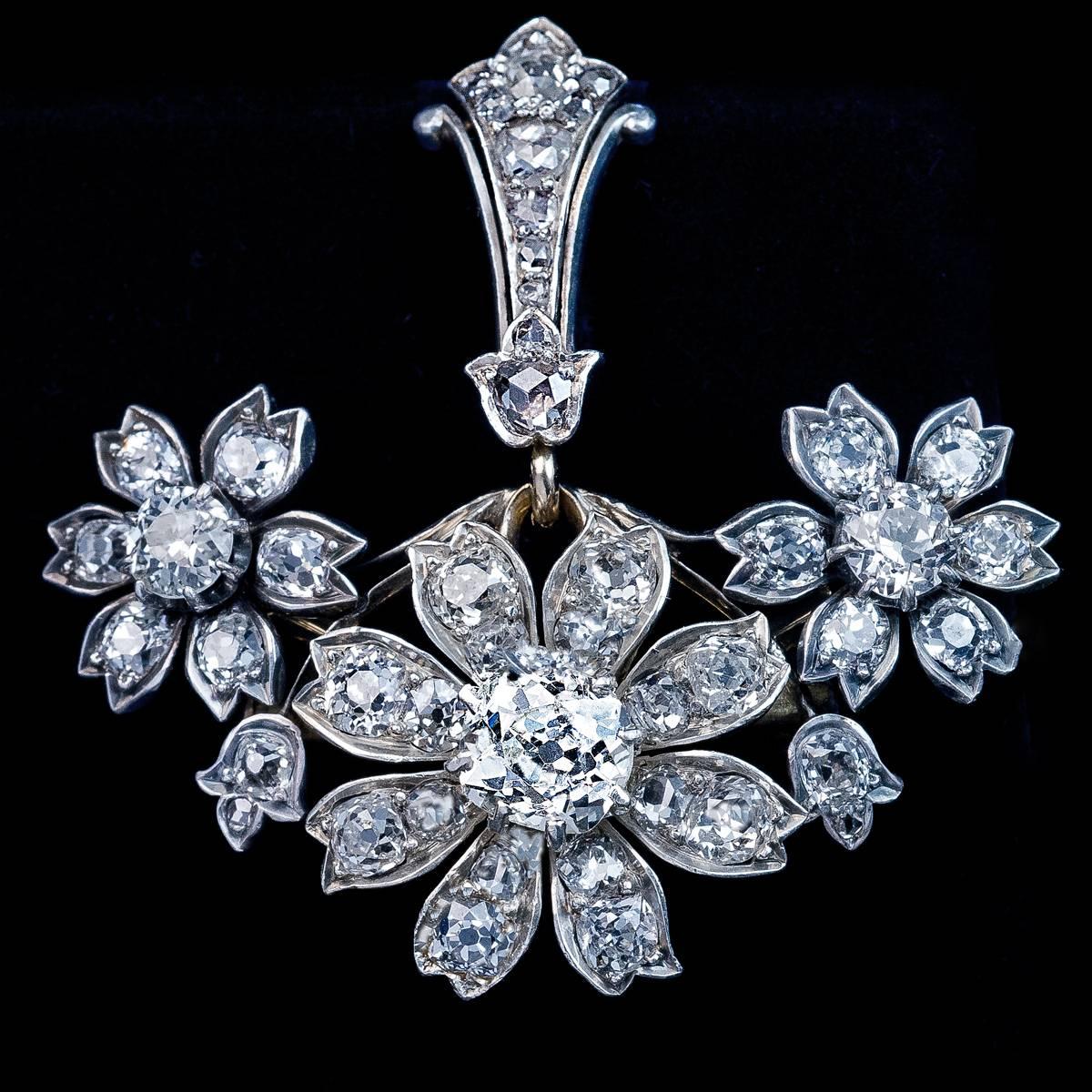 A convertible pendant / brooch of a floral design from the late 1800s, handcrafted in silver topped gold and set with old cushion cut, old European and old mine cut diamonds. The bail is embellished with old rose cut diamonds.

The center diamond