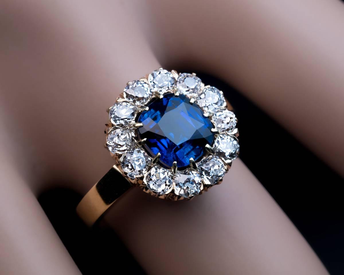  circa 1910

A 14K yellow gold ring is centered with a cushion cut natural sapphire (7 x 6.55 x 4.25 mm, approximately 1.71 ct) of a beautiful deep cornflower blue color framed by 12 sparkling bright white (G-H color) old mine cut