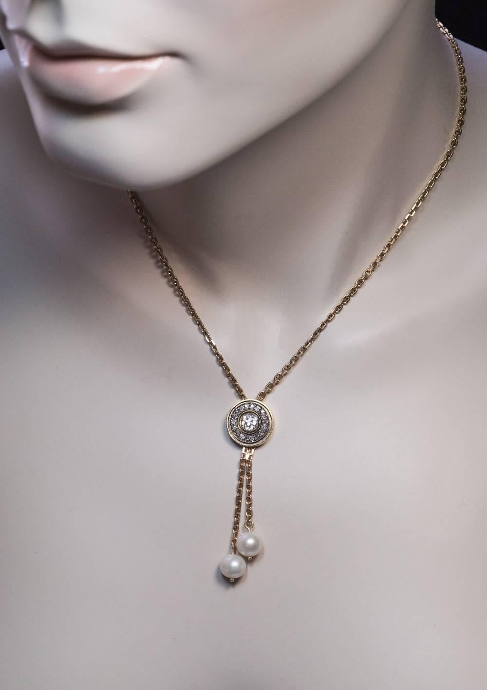 Made in St. Petersburg between 1899 and 1903

A 14K gold chain necklace is centered with a round diamond-set pendant with two dangling pearls.The center stone of the pendant is an antique cushion cut diamond (5.15 x 5.15 x 3.4 mm, approximately