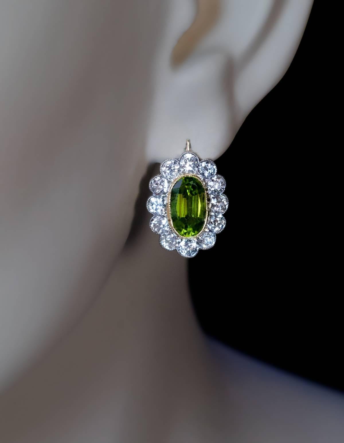 Made in Moscow between 1908 and 1917

14K gold handcrafted antique earrings are centered with oval faceted golden-green sparkling peridots set in gold milgrain bezels surrounded by sparkling old European cut diamonds set in silver over