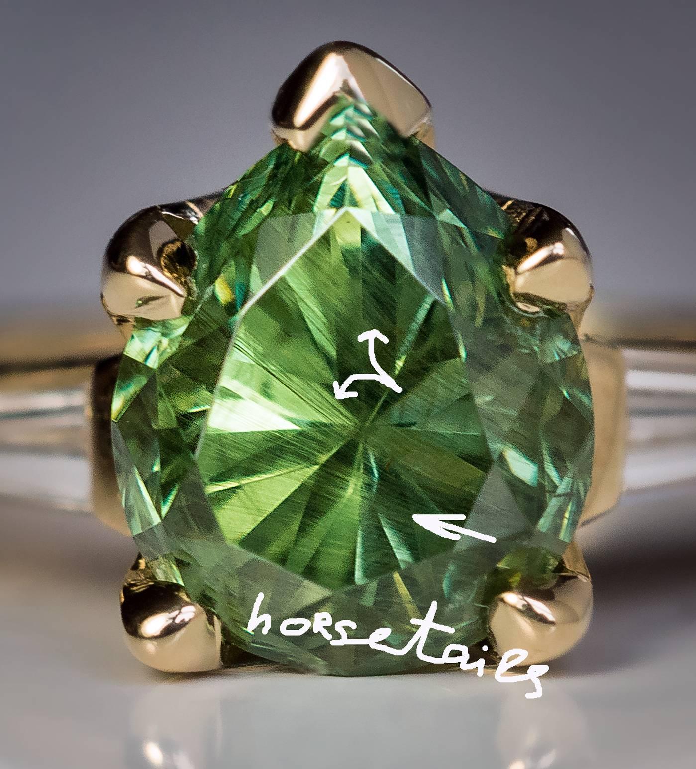 A contemporary 18K gold ring features a big and sparkling 2.85 ct pear cut Russian demantoid garnet flanked by two tapered baguette cut diamonds ( 0.44 ct total weight, E-F color, VS1 clarity).
Russian demantoids over 2 carats are very rare. The