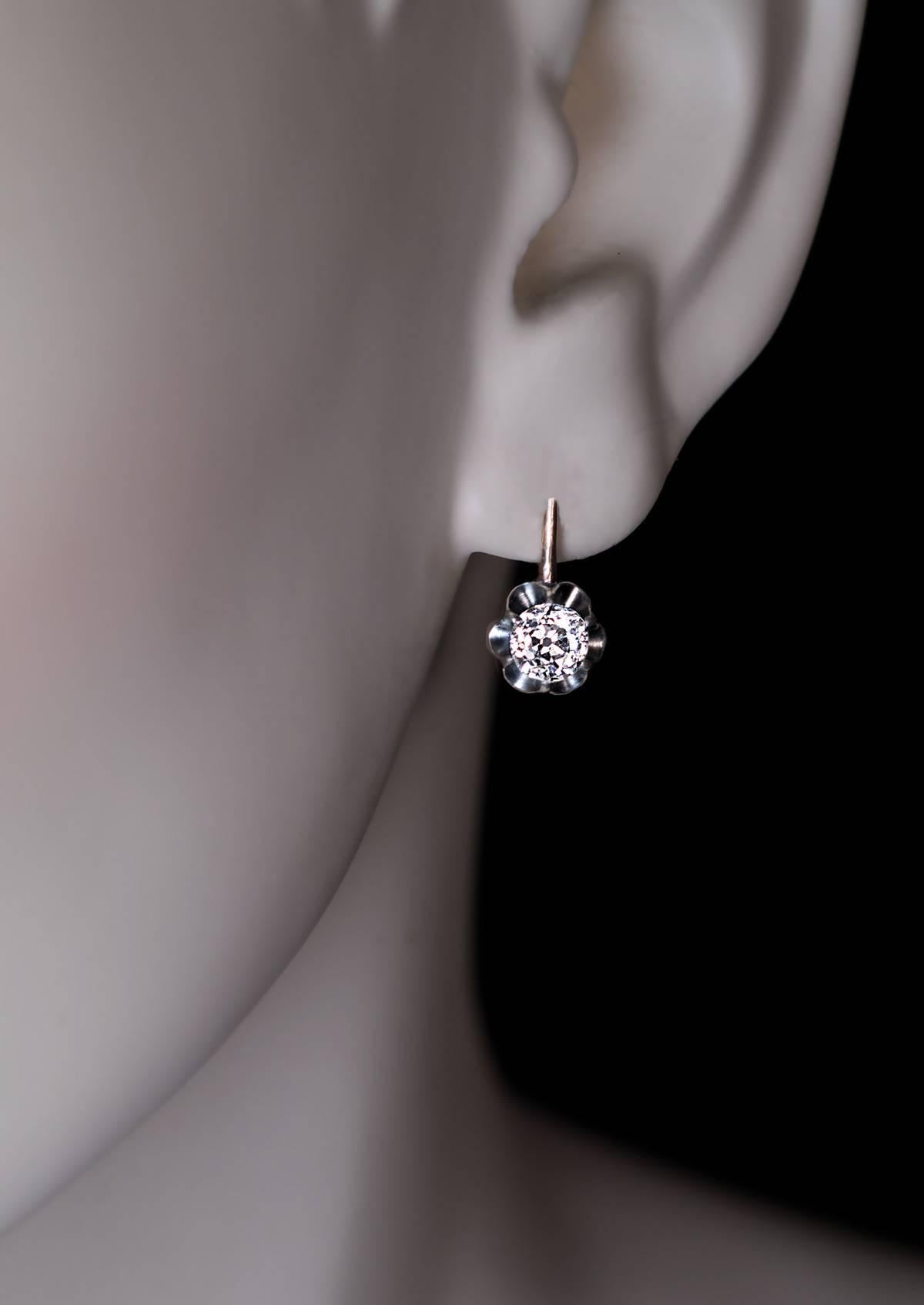 circa 1910
Two sparkling bright white old European cut diamonds (approximately 0.60 ct and 0.62 ct, E-F color, SI1 and SI2 clarity) are set in silver buttercup settings over 14K gold. The earrings are marked with later Russian control marks from the