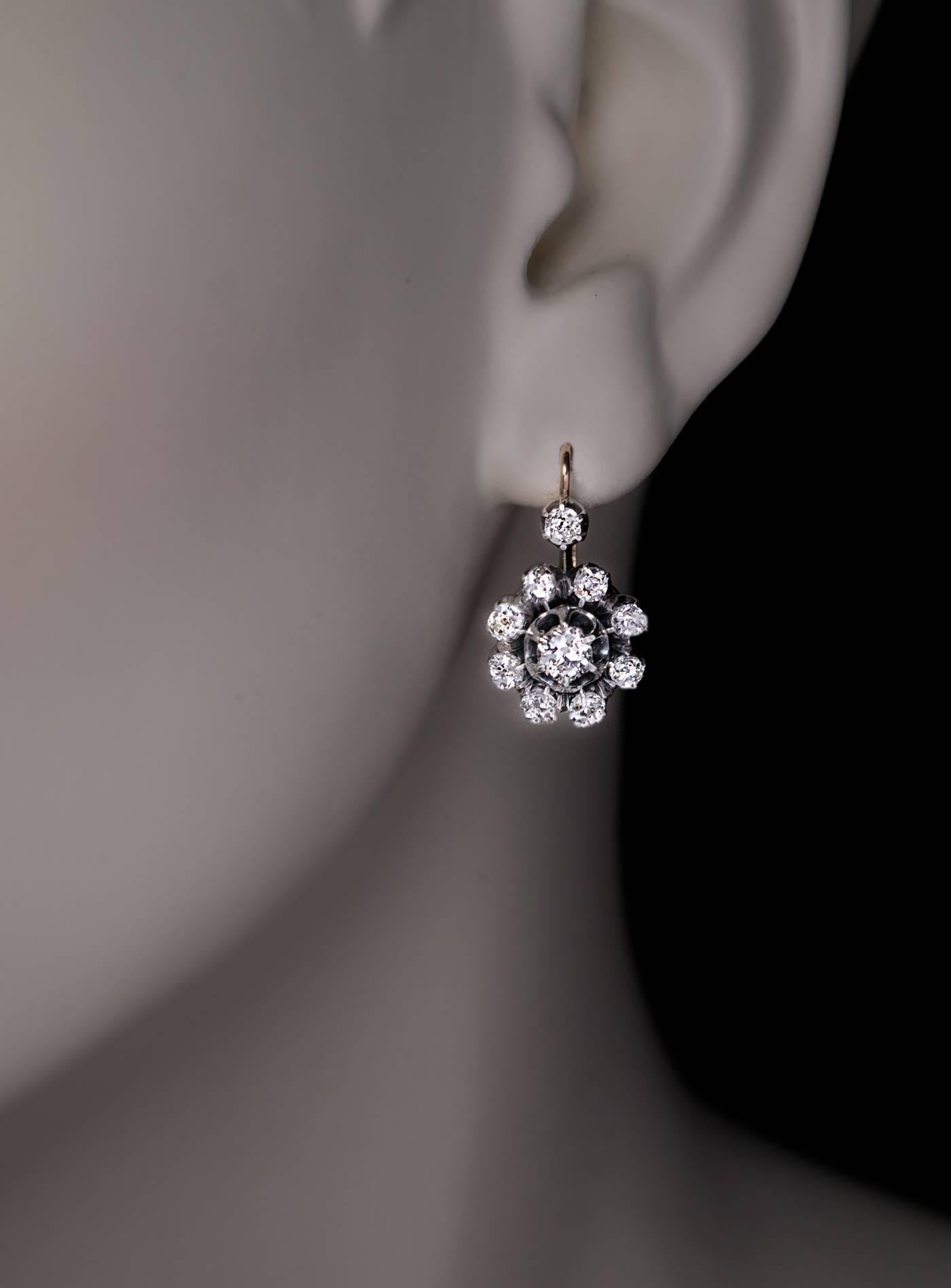 These snowflake-motif silver-topped 14K gold cluster earrings were made in Russia in the 1890s.
Each earring is centered with a bright white old European cut diamond (approximately 0.35 ct, F color, VS-SI clarity) encircled by sparkling old mine cut