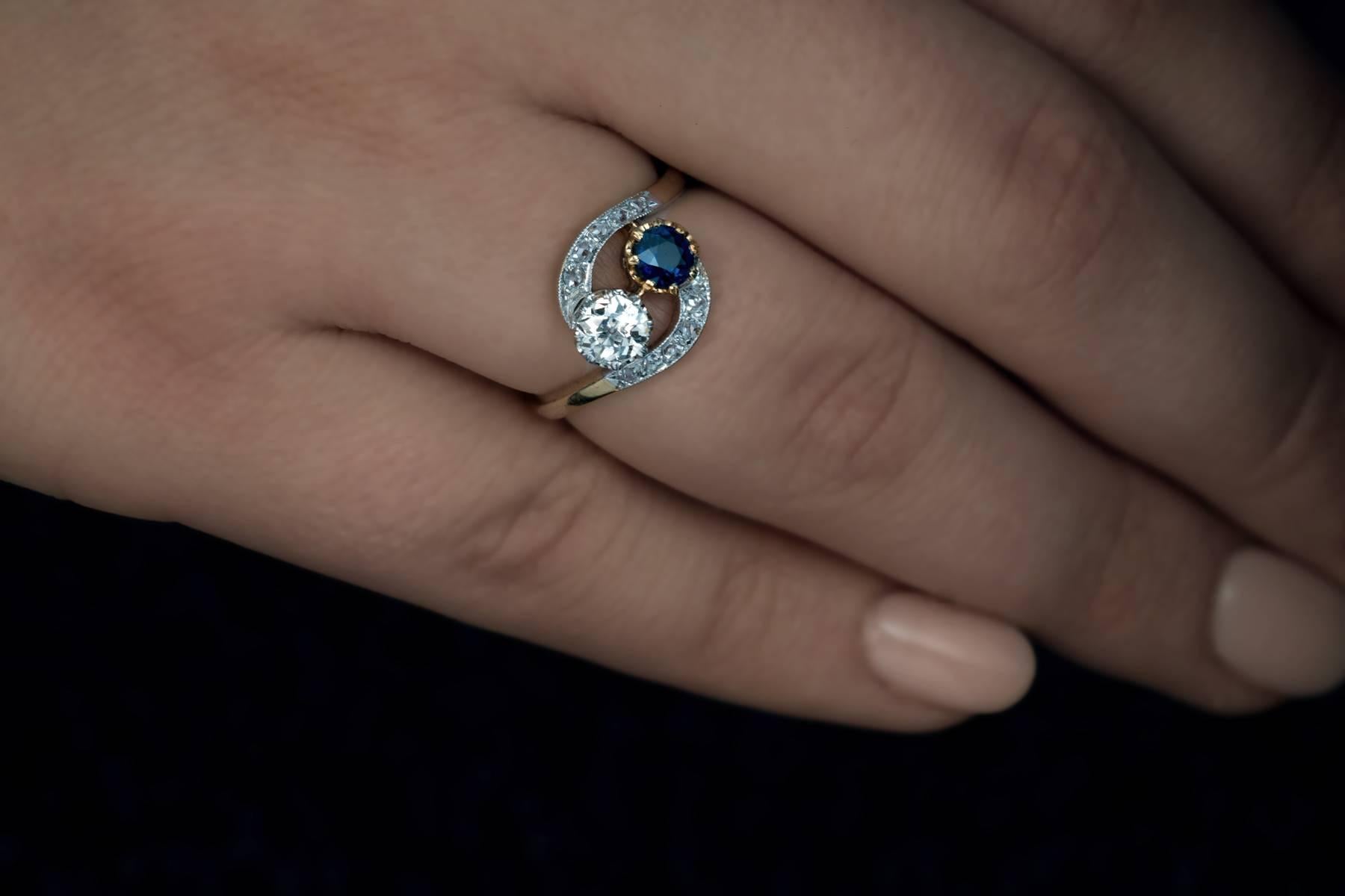 This antique platinum-topped 18K gold crossover engagement ring with interlocking diamond and sapphire was made in France around 1905.  The French call this type of engagement ring “toi et moi” (you and me). The main diamond is a sparkling old