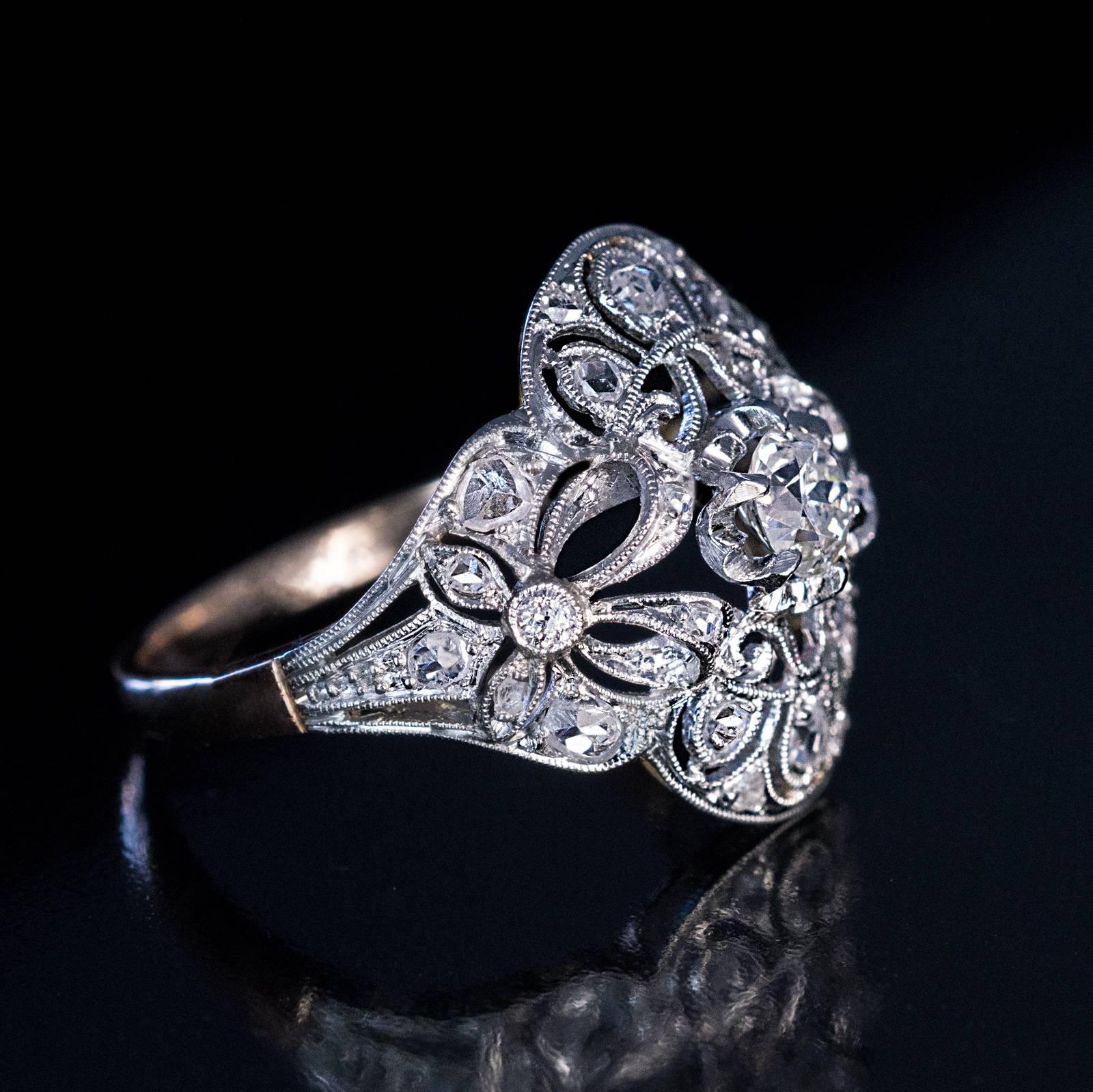 Edwardian / early Art Deco, circa 1910
An antique platinum-topped 18K gold openwork milgrain ring is centered with a sparkling old European cut diamond (4.7 x 3 mm, approximately 0.42 ct, H-I color, SI2 clarity) flanked by two bows and lace-like