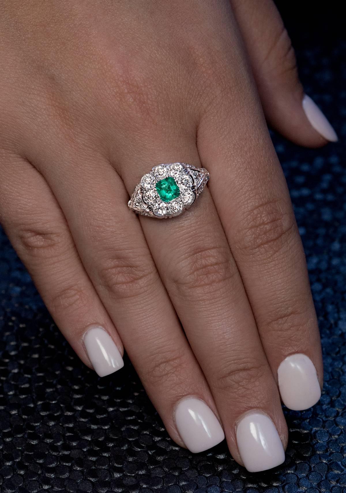 Circa 1925
This vintage platinum ring is centered with an emerald-cut emerald of a vivid bluish green color (5.63 x 5.14 x 3.55 mm, approximately 0.75 ct) framed by seven bright white (F-G-H color, SI clarity) old European cut diamonds. The