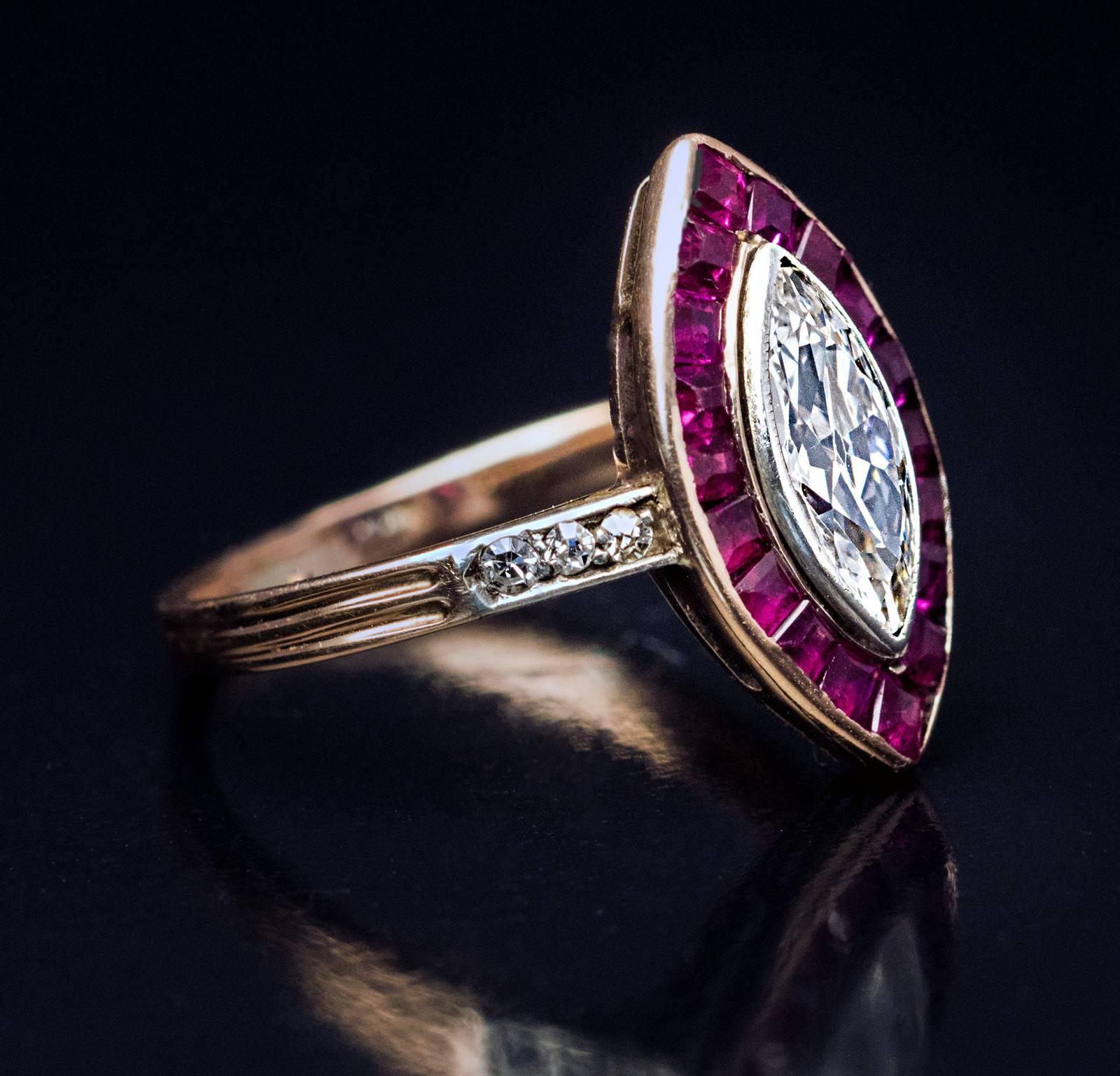 An antique Edwardian era navette shape engagement ring is centered with an old marquise cut diamond (9.6 x 4.3 x 2.5 mm, approximately 0.60 ct, H color, VS1 clarity) framed by channel set calibre cut rubies (estimated total ruby weight 0.80 ct). The