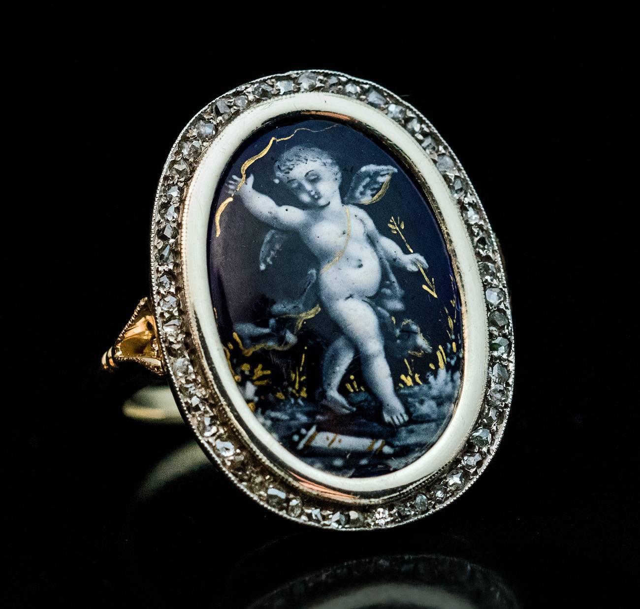 A Victorian era silver topped gold ring features a Renaissance style French Limoges enamel miniature of Eros / Cupid, the Greco-Roman god of erotic love, desire and affection, finely painted in white & gray enamels on a cobalt blue ground with gold