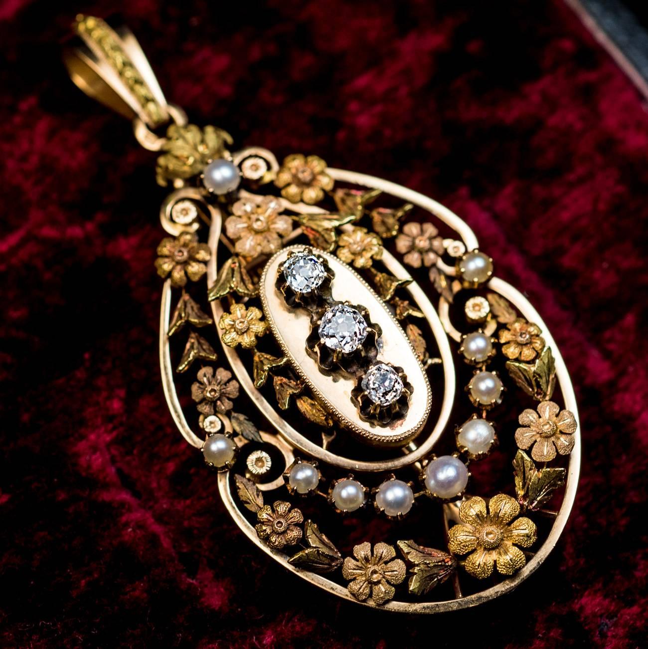 1880s -1890s
An antique 18K gold pendant with finely chased and engraved multi-tone gold flower garlands, is embellished with half pearls and three old mine cut diamonds.
Estimated total diamond weight is 0.82 ct.
The pendant is marked with three