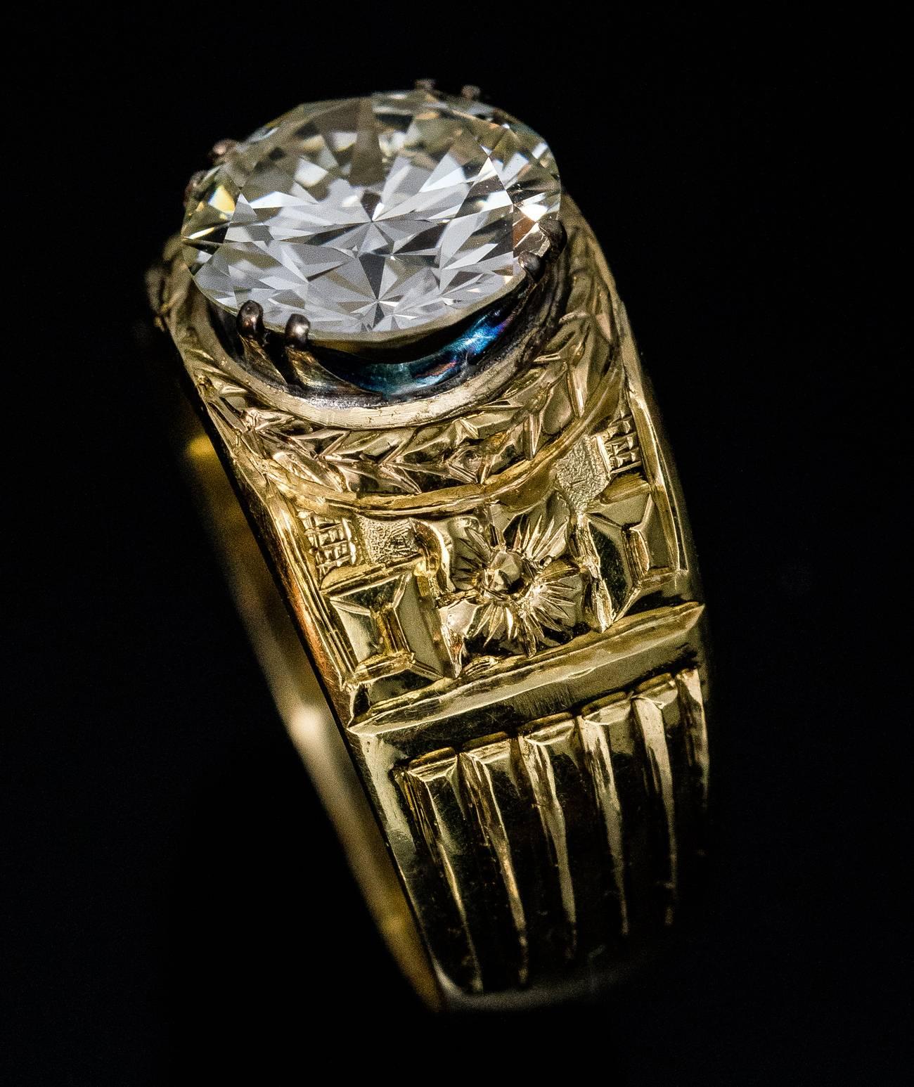 A vintage Russian 18K gold men’s ring features a 3.48 ct transitional (1930s) brilliant cut diamond set in silver prongs. The diamond is encircled by a carved laurel wreath and flanked by floral and geometric designs.
The diamond measures 9.85 x 5.7