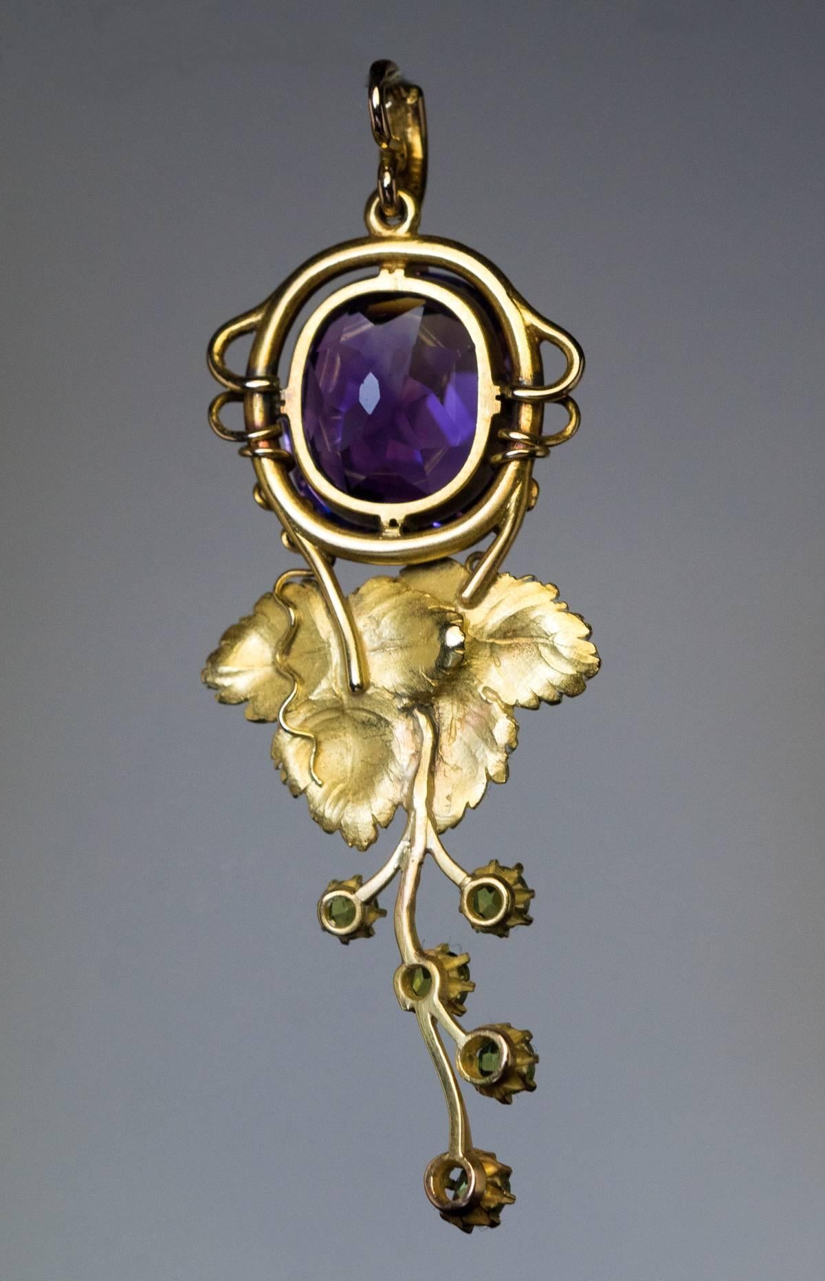 Made between 1908 and 1917
An antique Russian gold pendant is designed in Art Nouveau taste as a stylized grape vine with finely modeled green gold grape leaves. The pendant features a rare Siberian amethyst and five green demantoid garnets.
The