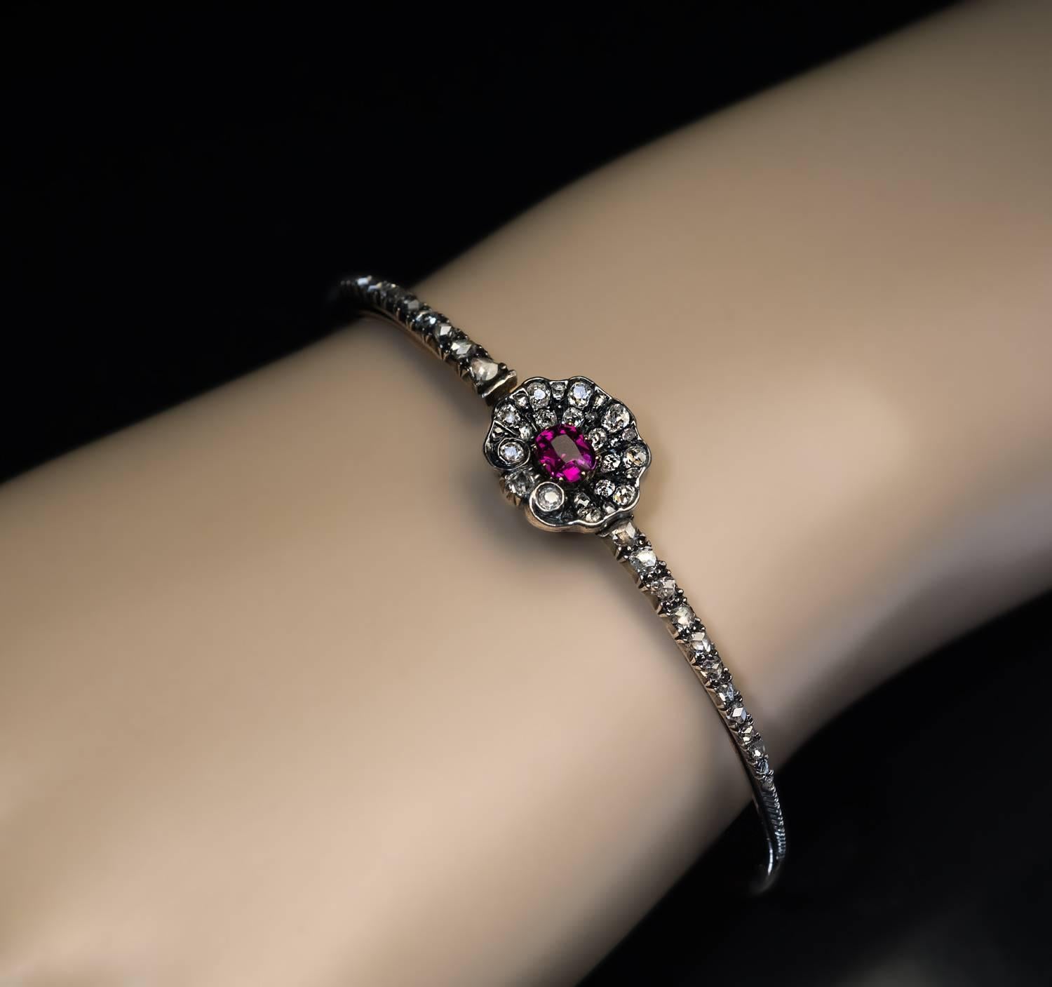 Circa 1850

An early Victorian era silver-topped 14K gold bangle bracelet is centered with a ruby and diamond stylized shell flanked by graduating rose cut diamonds.

The cushion cut ruby is of an excellent color and clarity and likely of Burma