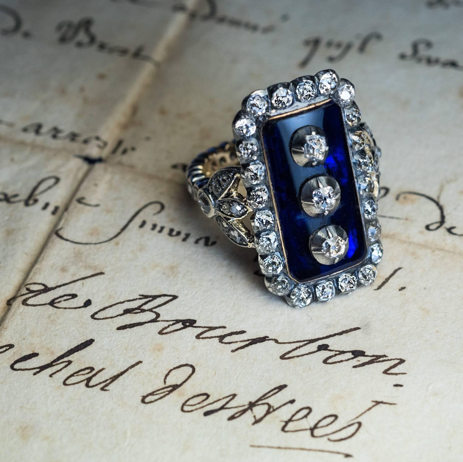 This impressive late 18th century, circa 1790, silver-topped gold ring is vertically set with a large cobalt blue glass plaque centered with three old cut diamonds set in silver cut down settings. The glass plaque is framed by 24 chunky old mine cut
