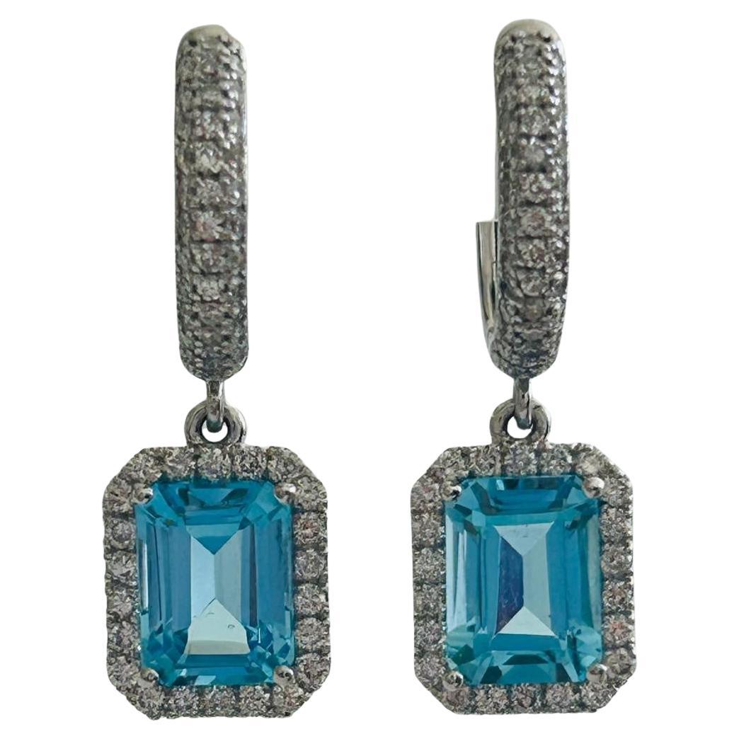 Add a touch of sophistication to your jewelry collection with these stunning drop earrings, featuring vibrant, emerald-cut blue topaz gemstones that exude timeless elegance. Each dazzling topaz is surrounded by a halo of brilliant-cut diamonds,