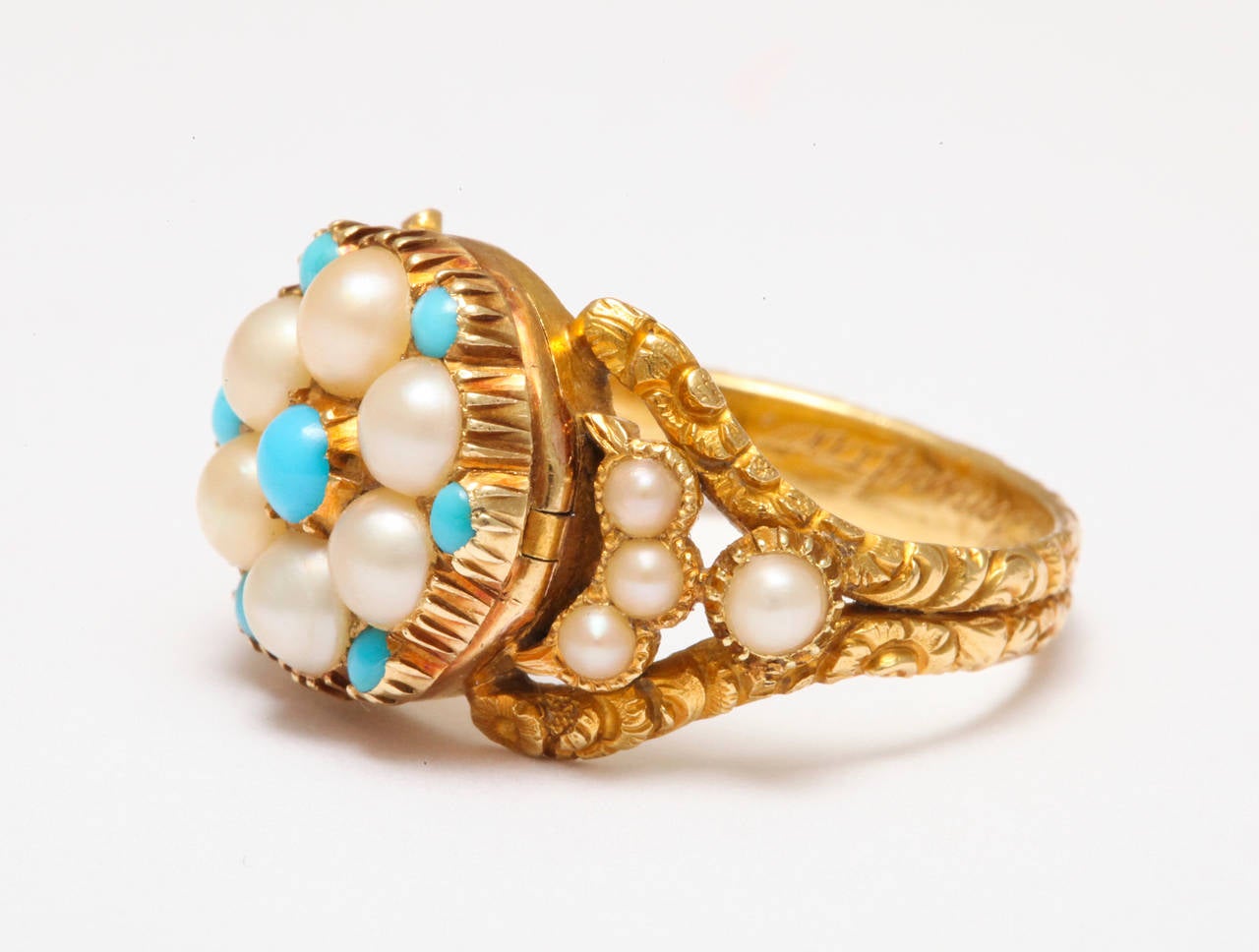 A high carat gold Georgian gem of a ring in which the  engraving, the hand made setting, and the  glow of the turquoise and pearl gems are all  extraordinary. Locket rings from the early nineteenth century are rare indeed. We felt  extremely