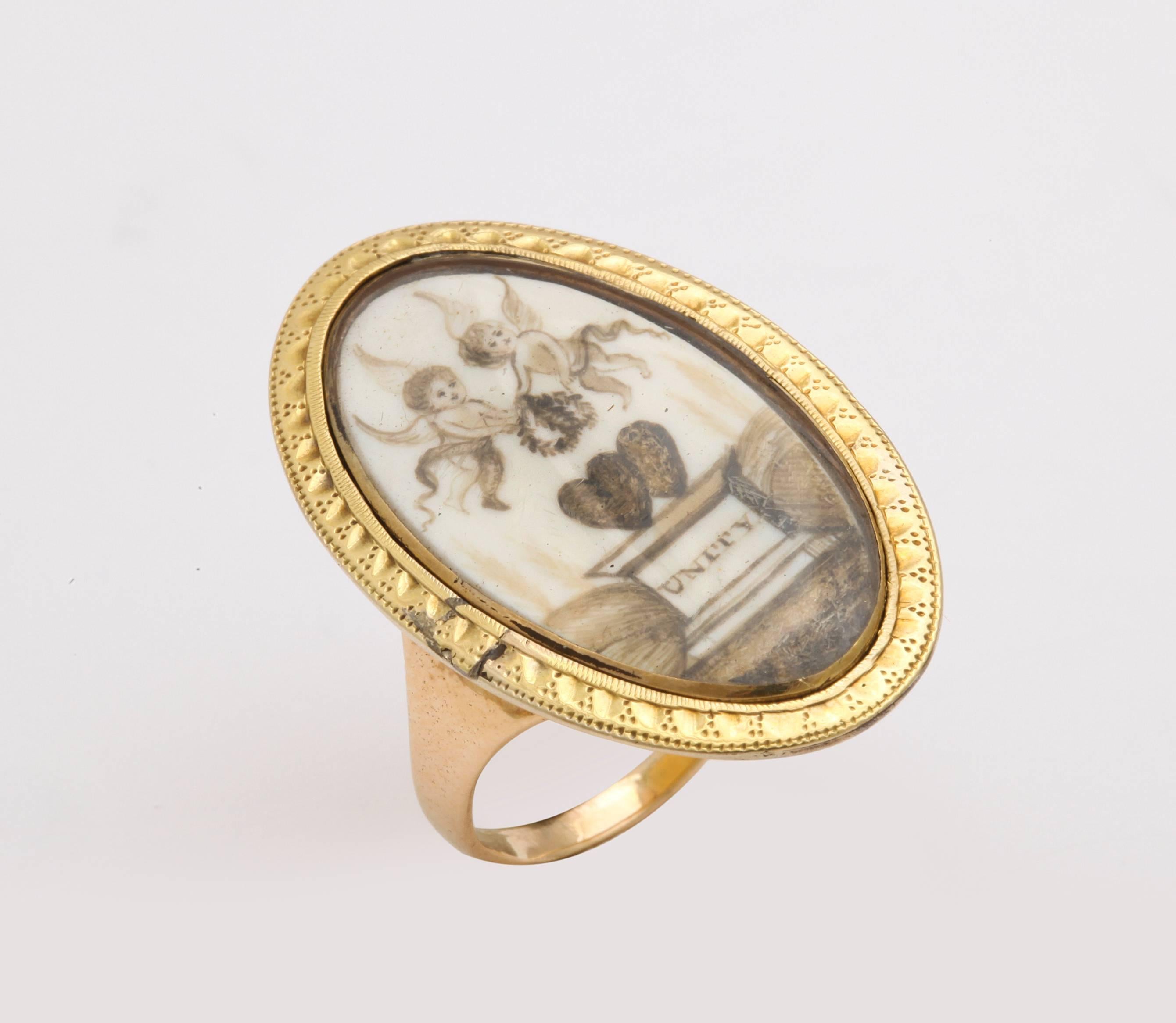 A 15kt  oval Georgian love token tells a story of enduring love, with a miniature painting of two youthful cupids, two entwined hearts and the story of love made in heaven til death do us part. All of this is beautifully painted and preserved on a