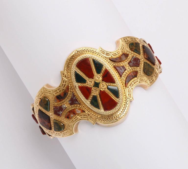 A Victorian Scottish Agate bracelet of hand sculpted specimen moss agates , red jasper and bloodstone are set in a balanced array in high carat gold that has been hand engraved around the entirety. At the bracelet center is an oval plaque with