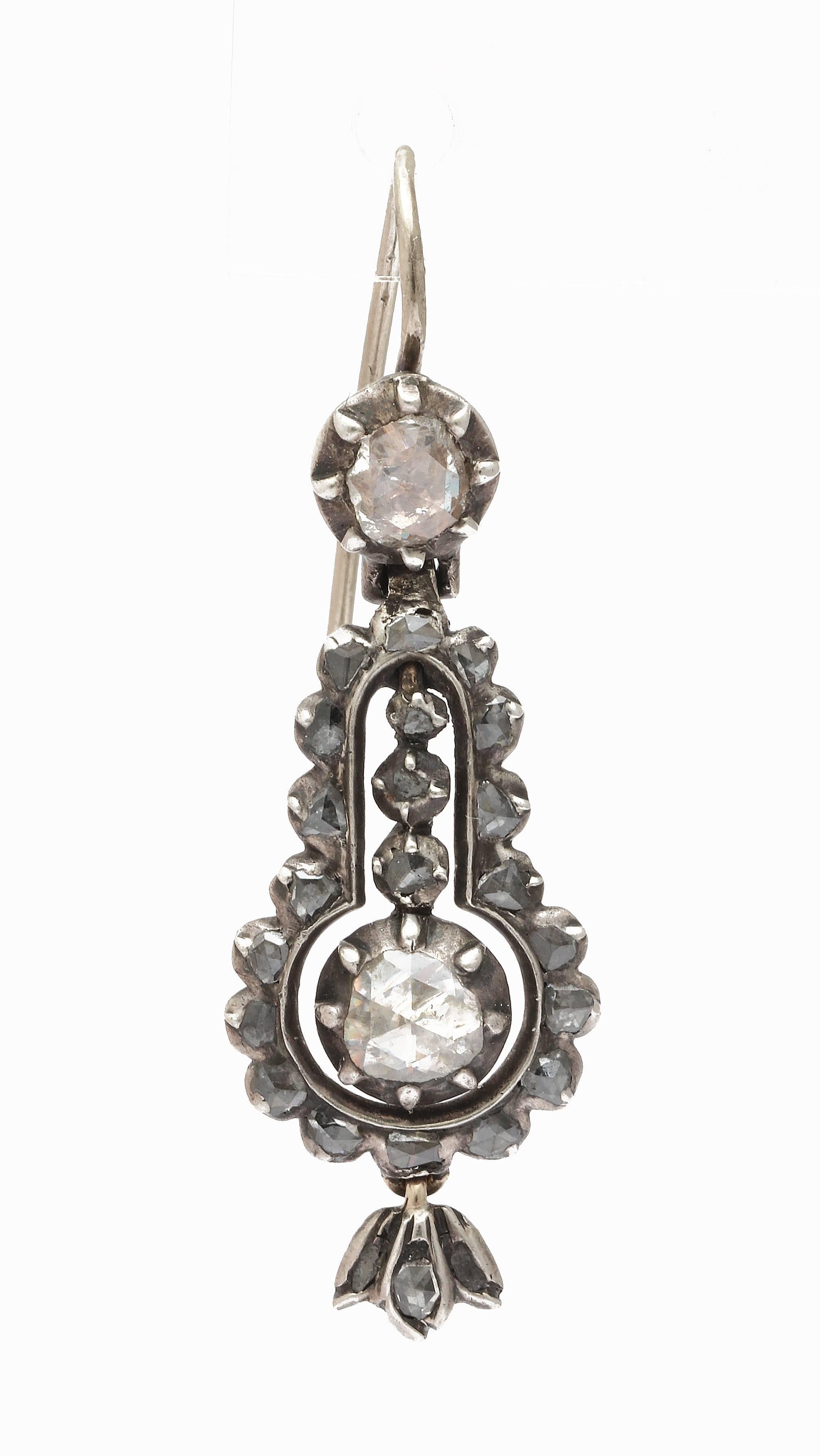 Georgian diamond earrings in the form of lyre flicker in their closed back settings. Tiny floral buds are suspended at bottom. The diamonds are set in silver and 15 Kt gold in the Georgian manner.  They are fine and multi faceted rose cuts. The