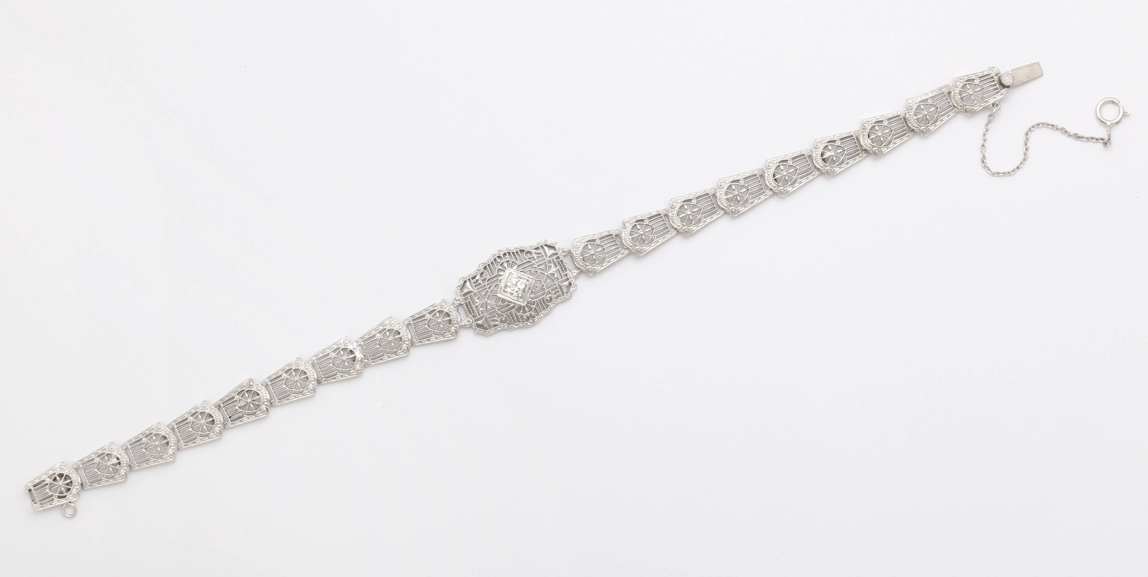 A delicate, White 14kt gold bracelet has links of  stunning architectural design set with a central diamond. The bracelet is an example of the classic filigree work of the Art Deco era.  The gold is fine and reminiscent of lace yet strong. Fine