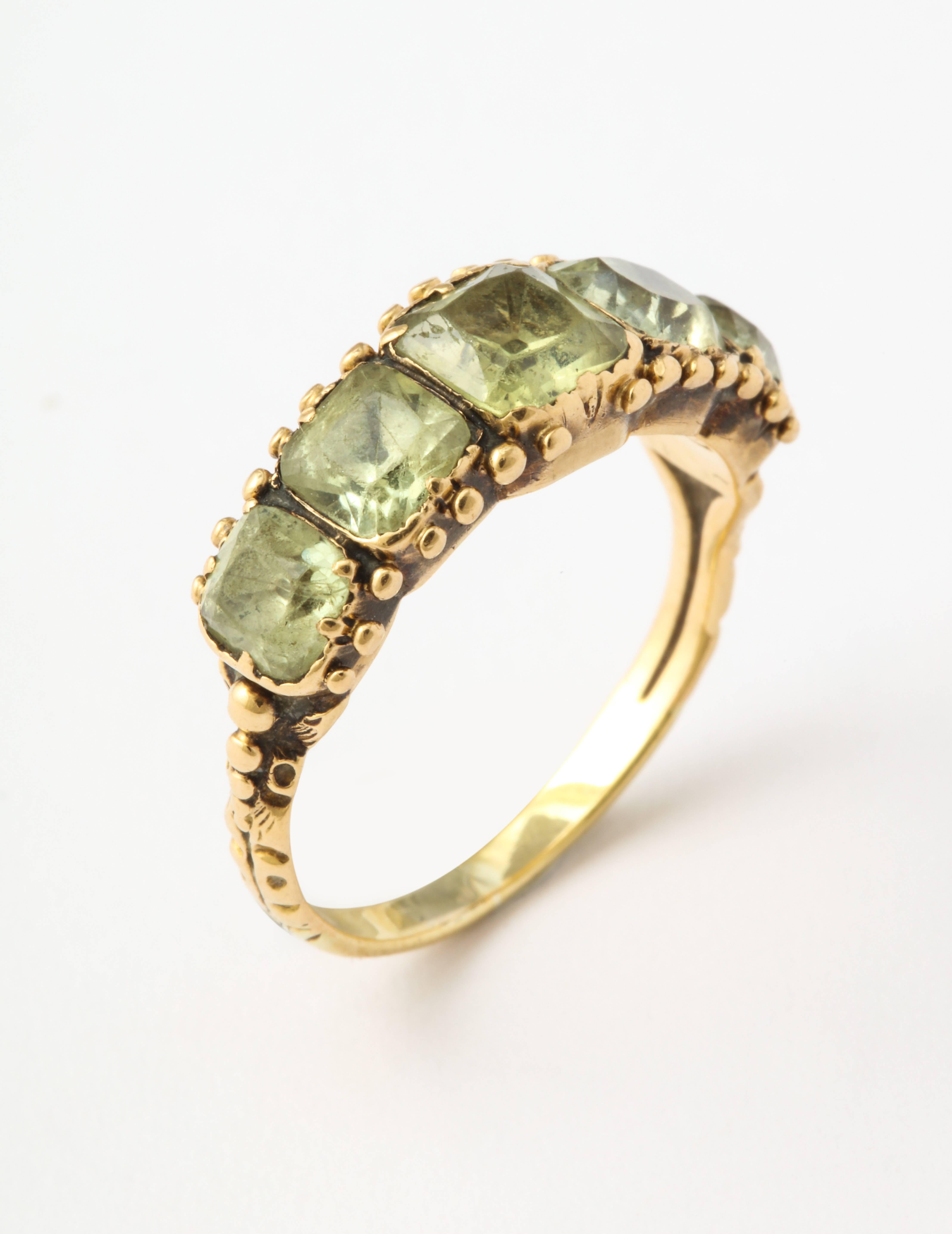 The yellow green akin to the green eyes of a pet cat or a mountain lion, is the color of the five european square cut stones of this Georgian half hoop band. The stones, of generous size, are in beaded settings of 15 kt gold. The rings shoulders