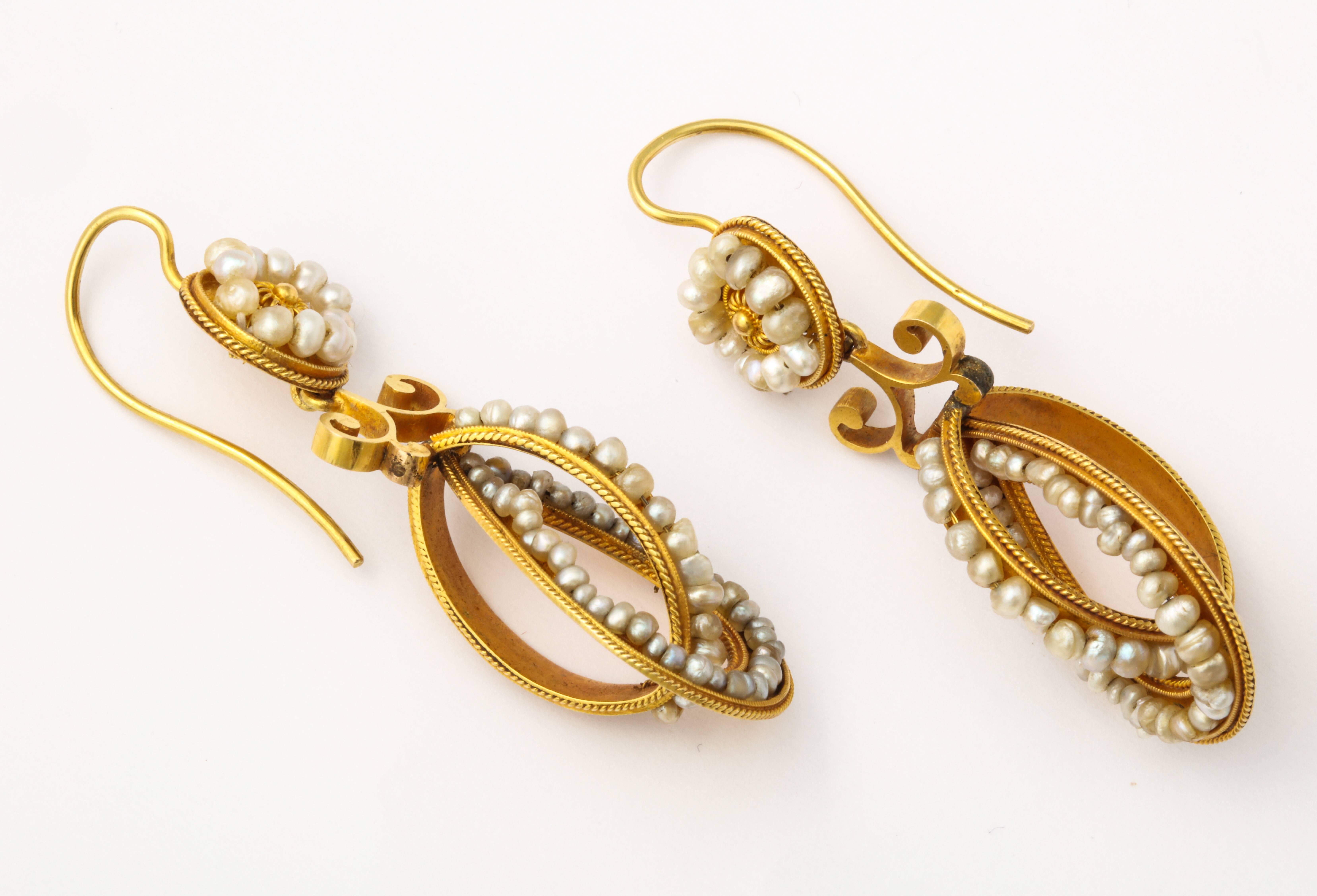 Light on the ear, seed pearls line opposing ovals of 14kt or 15kt gold as they drop below a flower form just below the lobe. Unquestionably an unique and romantic Victorian look, the earrings are European c. 1860. Condition is fine. Measurements 2