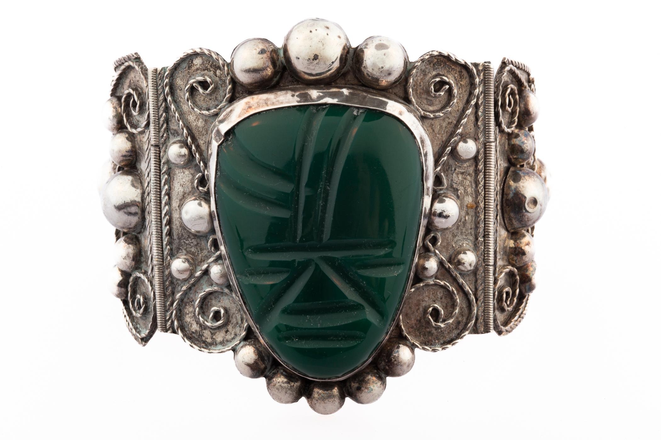 Un bracciale messicano insolito e in ogni modo audace, realizzato da Icuala. L'audacia si manifesta nella larghezza del bracciale, nella testa peruviana in bachelite intagliata al centro e nelle grandi sfere d'argento sulle maglie laterali. Non vi è