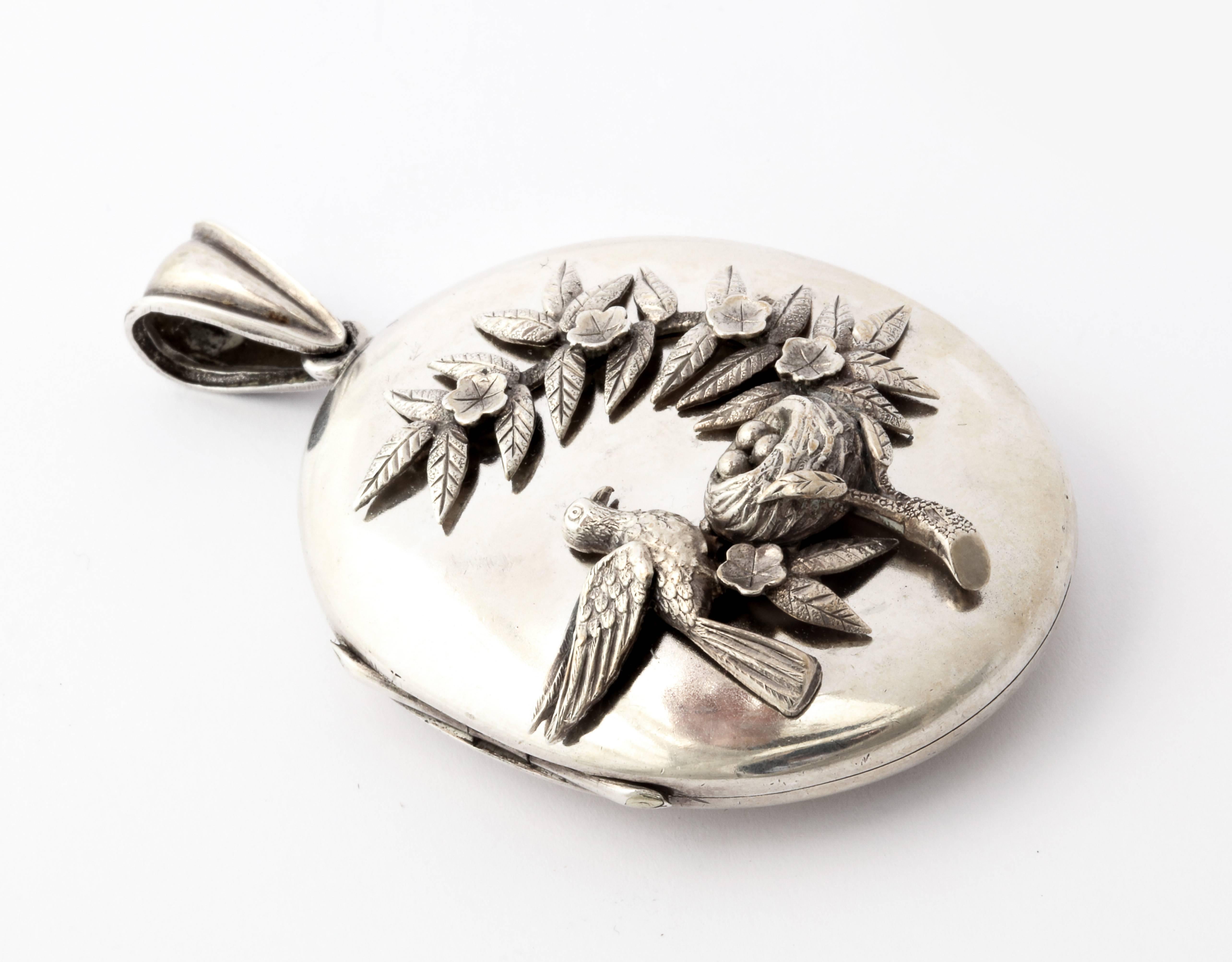A very lovable locket proudly shows a highly detailed relief of a parent bird at its nest, overseeing three eggs. The bird's feathers, the nest and the floral spray in which the nest hides are all beautifully and individually engraved and raised