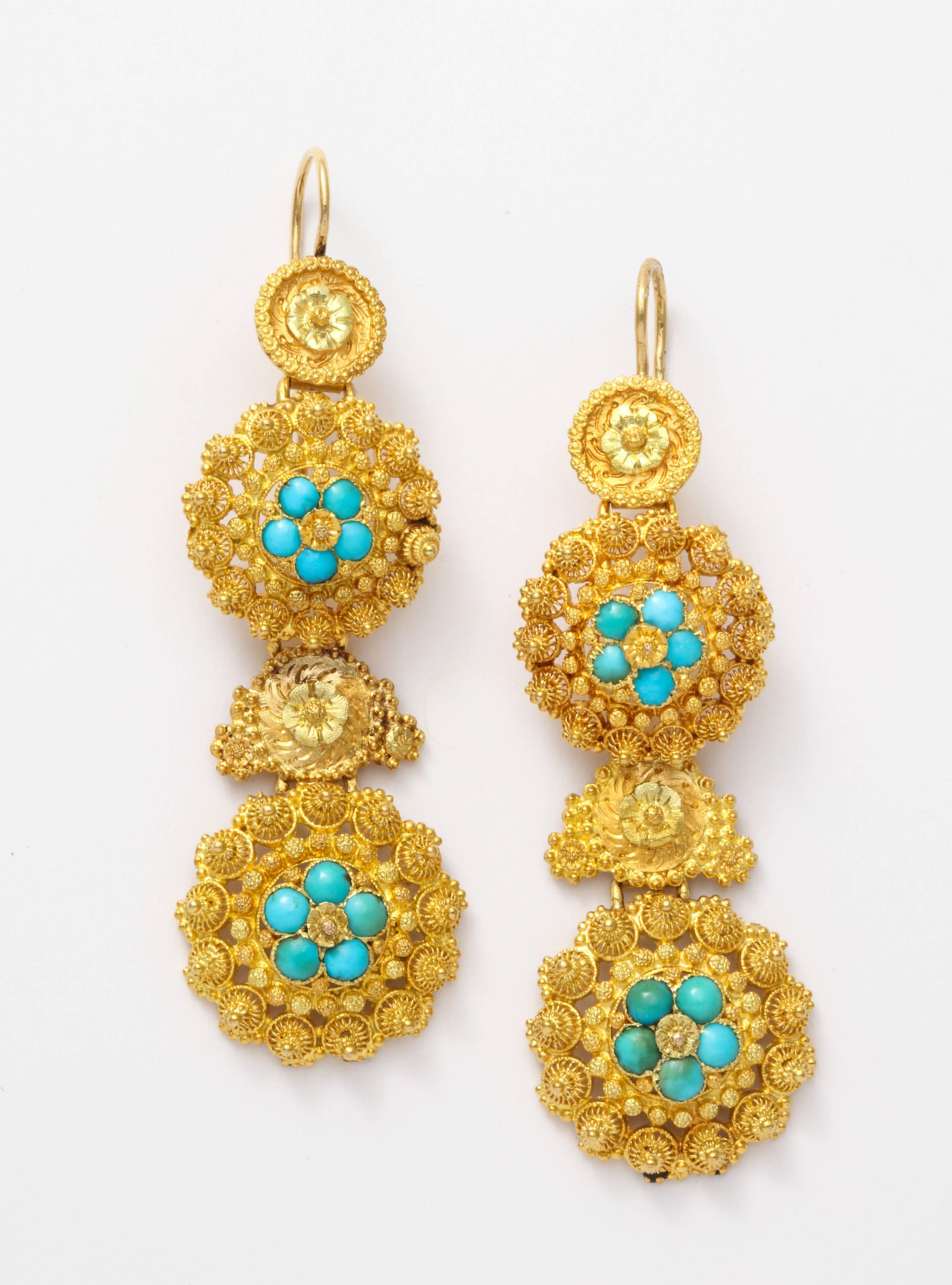 Fine cannetille work forms tight spirals in 18 kt gold that is punctuated with granulation and natural turquoise. There are four sections to these earrings and all are original to the 1840 construction. They are light on the ear. These are a