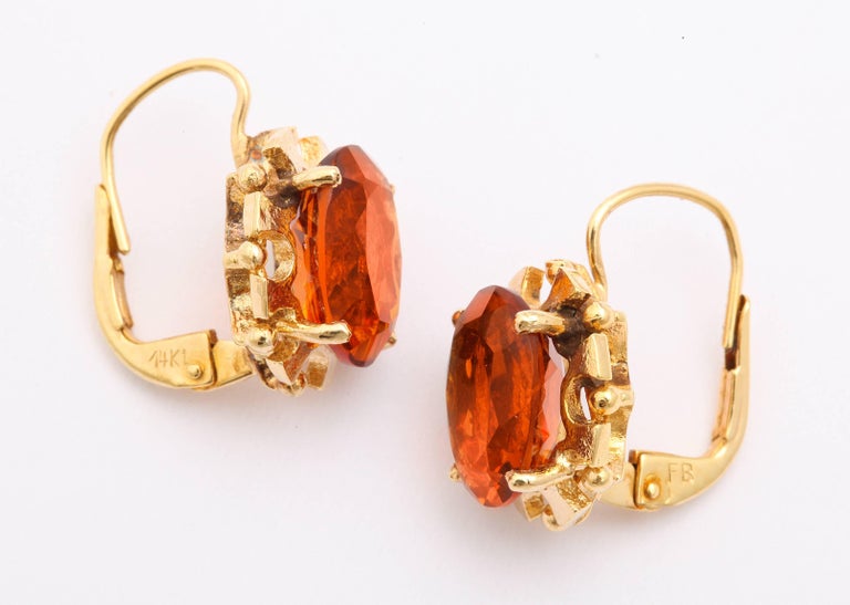 Like a beautiful sunset, rich tea color citrine earrings, set in 14 kt gold have lever backs. They originate from the mid 20th century. Round prongs hold the citrine while interest and texture are added from the gold surround of the saw tooth