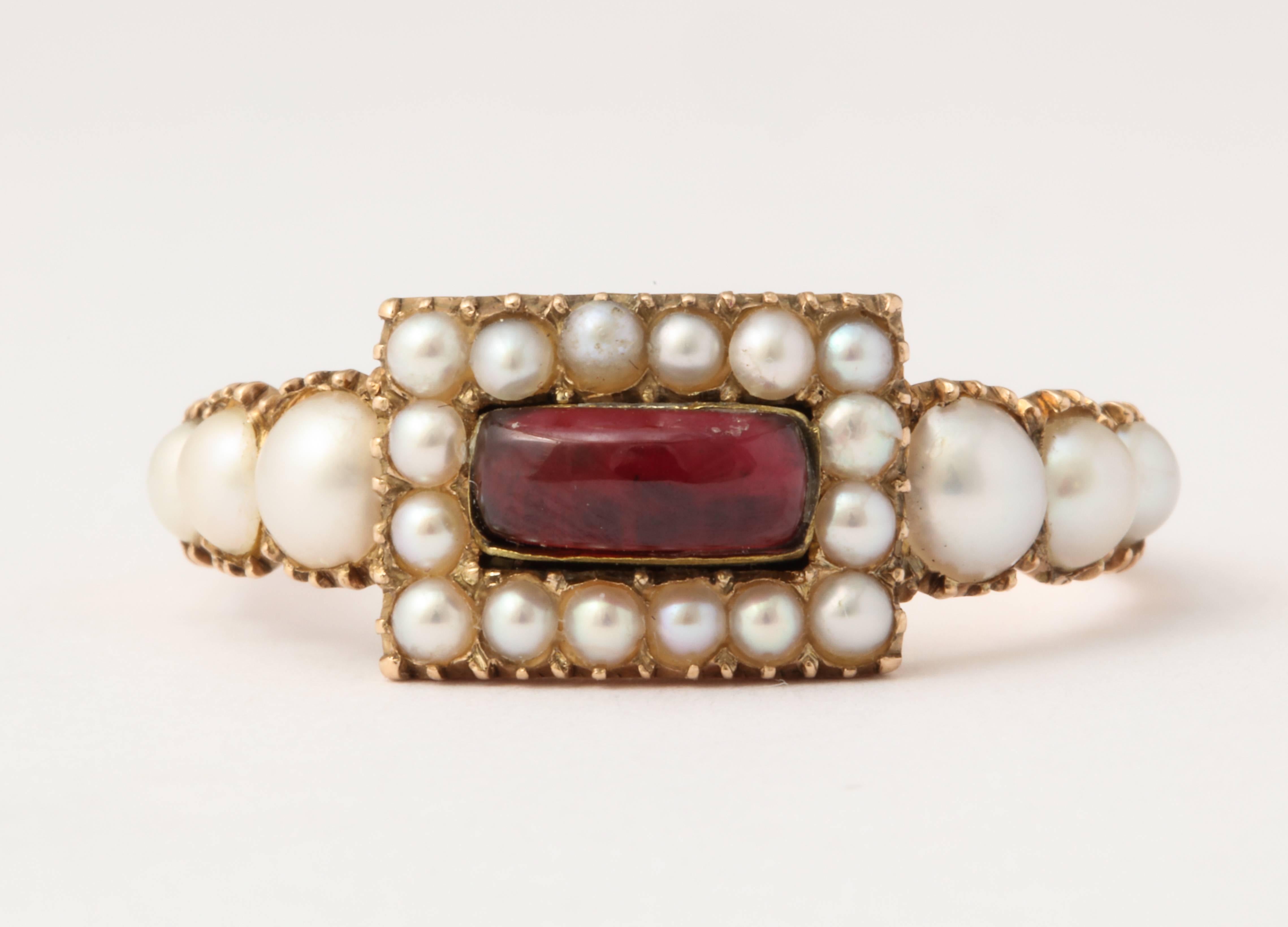 The gem quality is immediately visible in this treasure of a 15 kt gold natural pearl and garnet ring c. 1860. The pearls are lustrous and well matched as they frame the center garnet and spill graduated on the ring shoulders. Pearls were associated