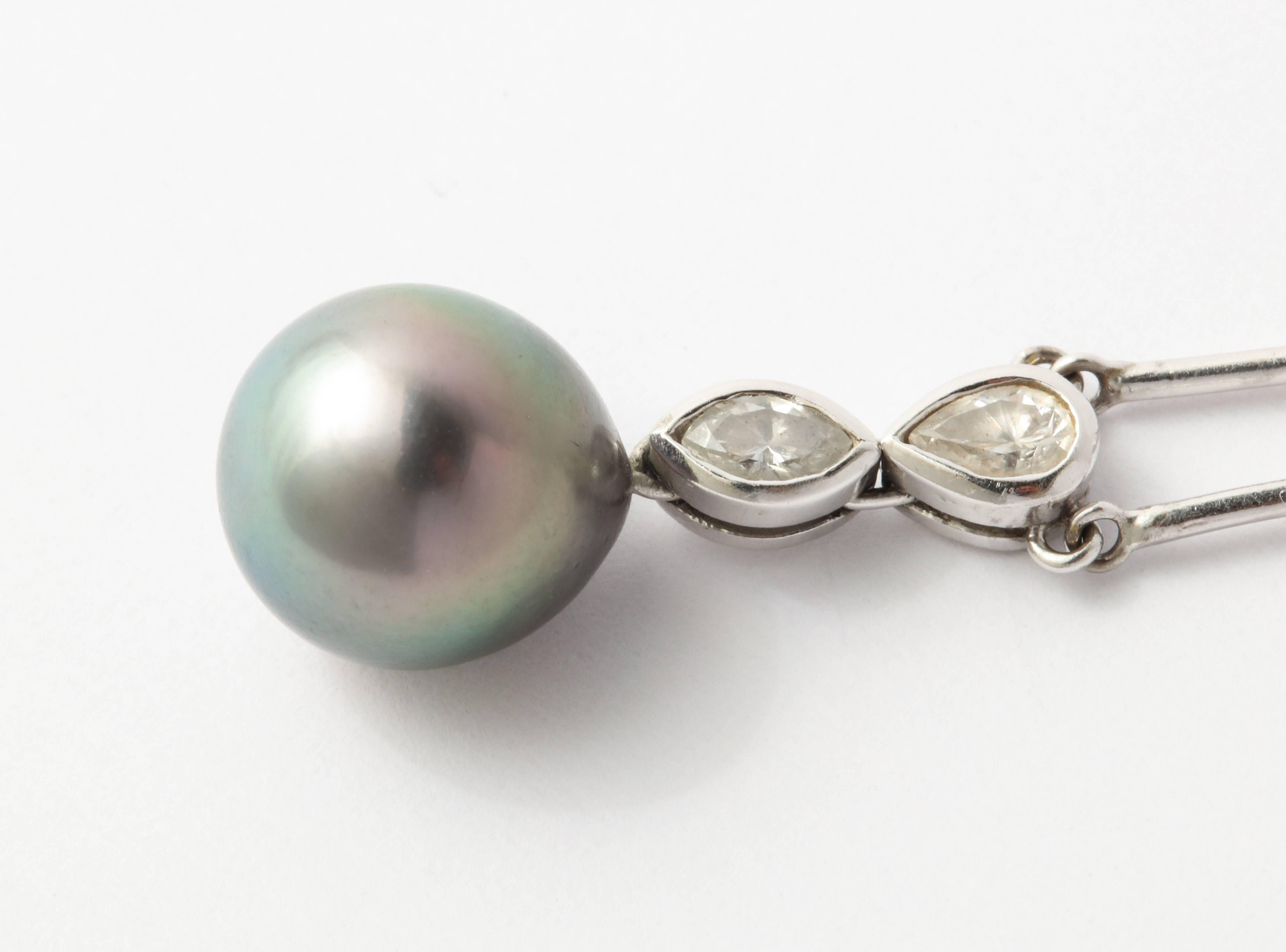 A flawless 11.3 mm teardrop Tahitian South Sea Pearl is thrilling in its smoothness and mirror like multi toned charcoal green color, topped by a pear shaped and marquise shape diamond..  When I study the pearl I am amazed that nature created this