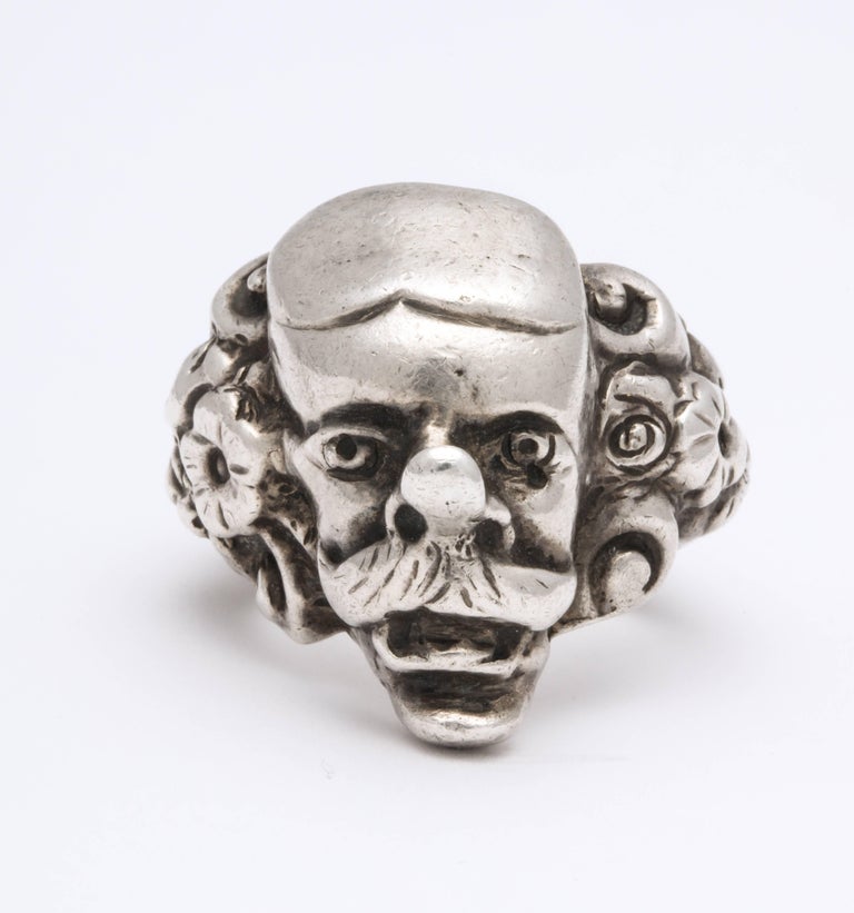 A weighty sterling silver ring, unisex, is sculpted and cast in amusing detail in as Capitano, a character of the Comedia dell' Arte Theatre. Deep engraving on the shank of repousse flowers is a suprise and lovely with the heavy male mustached mask.