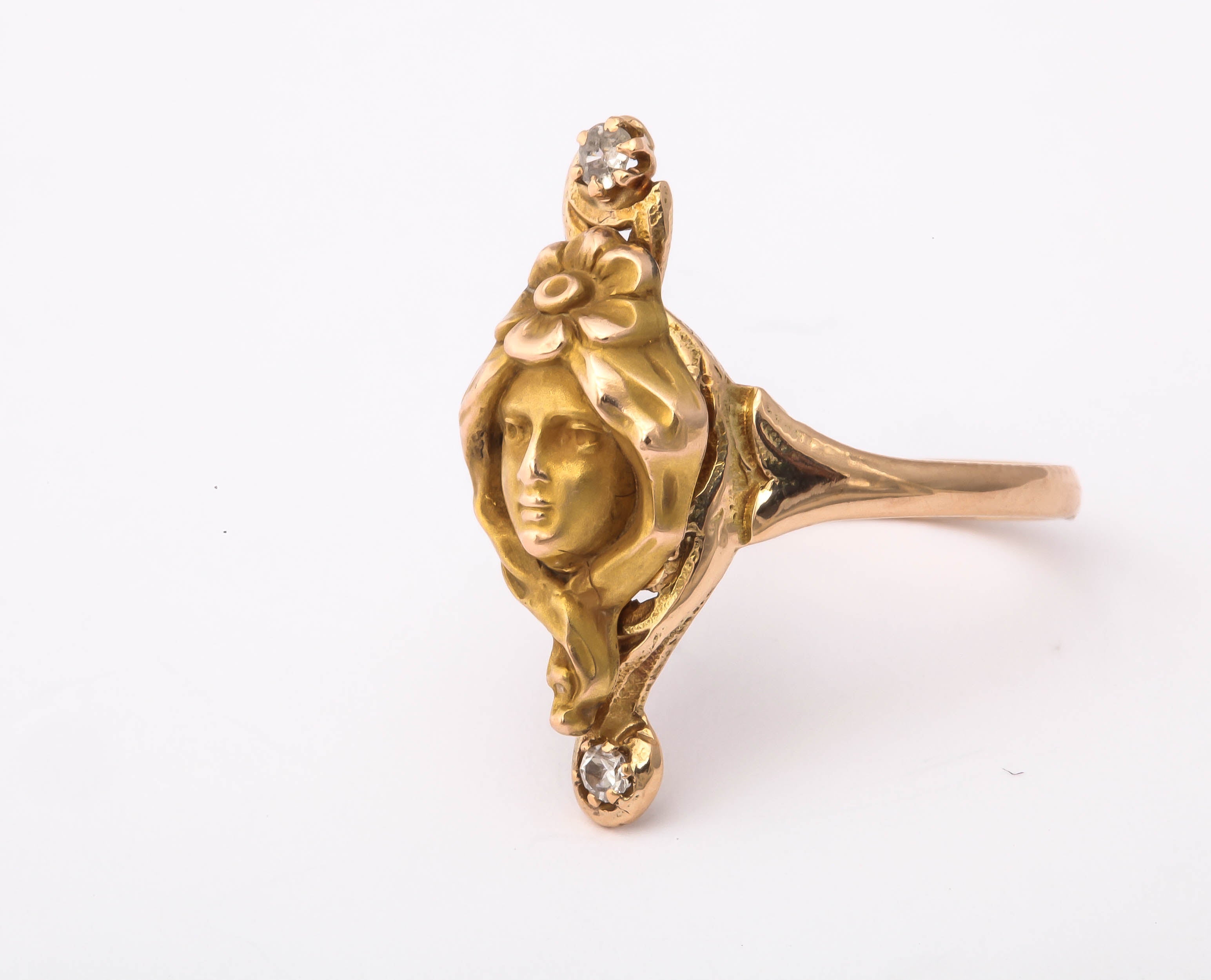 An Art Nouveau ring of perfection in 14kt gold brings you the ideal young woman,  wrapped in her long flower dressed hair and adorned with diamonds. The shape of the ring allows the lovely hair to drape around the face. A finely  detailed flower