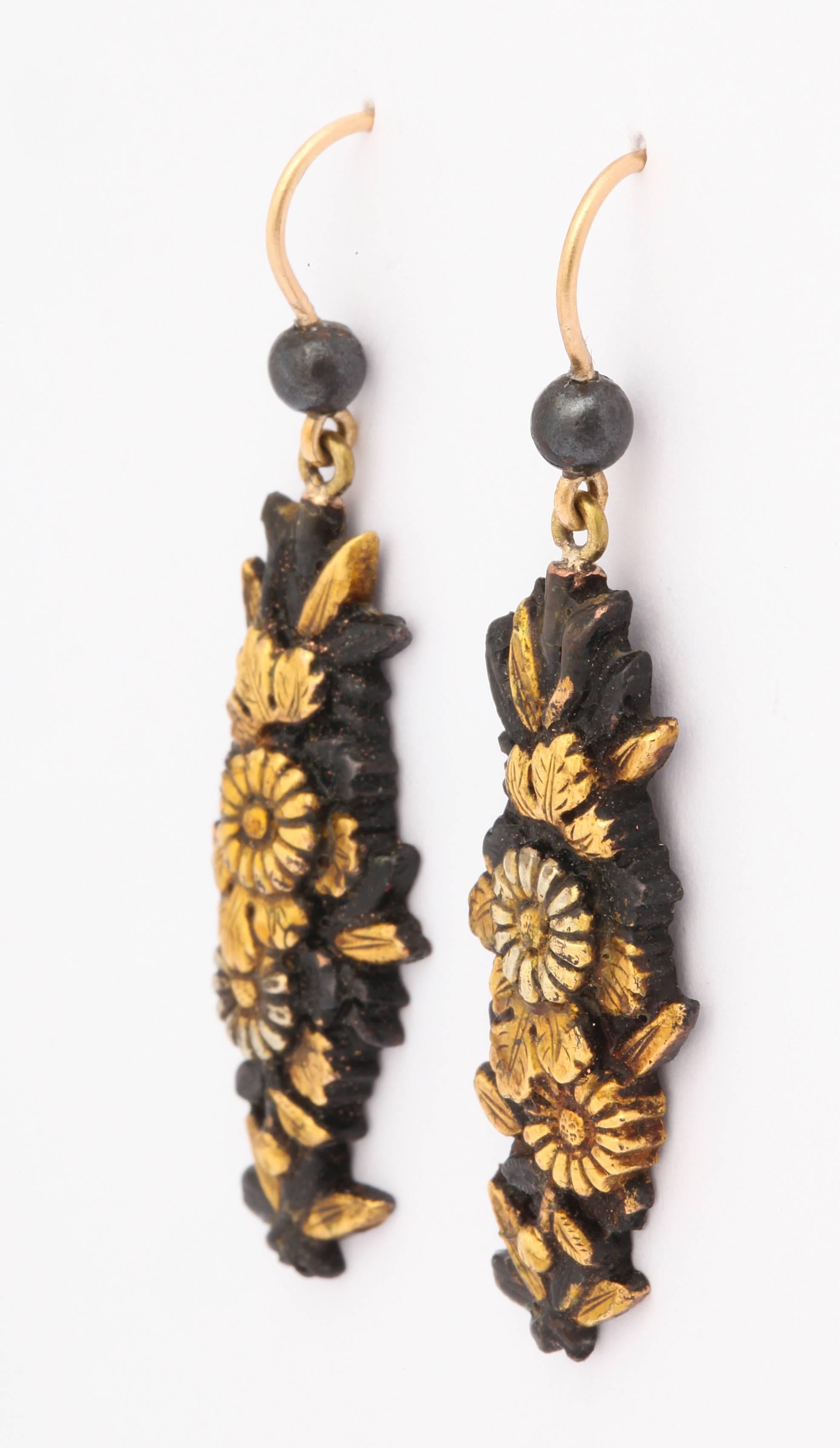 The Japanese esthetic that revered natures' wonders blooms in a pair of shakudo metal and gold earrings circa 1870 after Commodore Perry opened trade with Japan. The earrings are small chandelier or dangling forms covered with daisies.  Original to