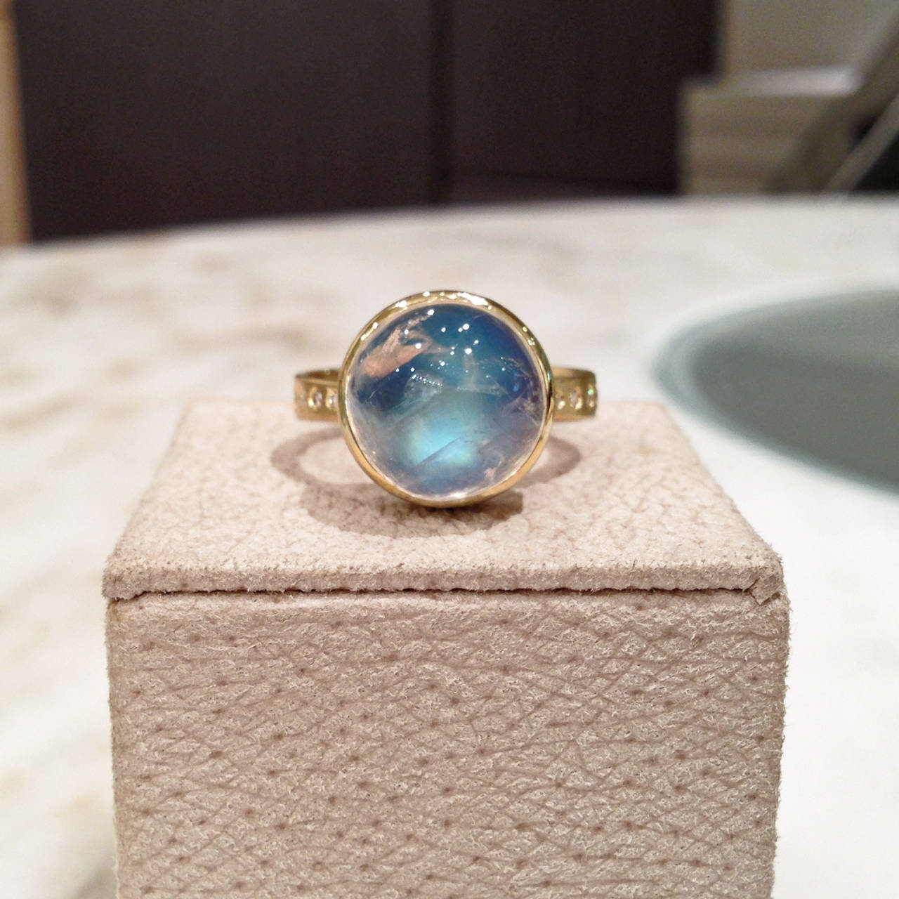 One-of-a-Kind Button Ring handcrafted in matte 18k yellow gold with a 7.94 carat cabochon-cut blue moonstone set in a shiny 18k gold bezel, and accented with eight VS1 white diamonds. Size 7.25 (can be sized).

Moonstone exhibits spectacular