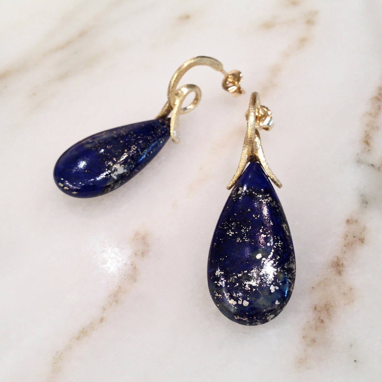 One-of-a-Kind Loop Earrings handcrafted in satin 18k yellow gold with lapis lazuli drops exhibiting stunning golden accents.